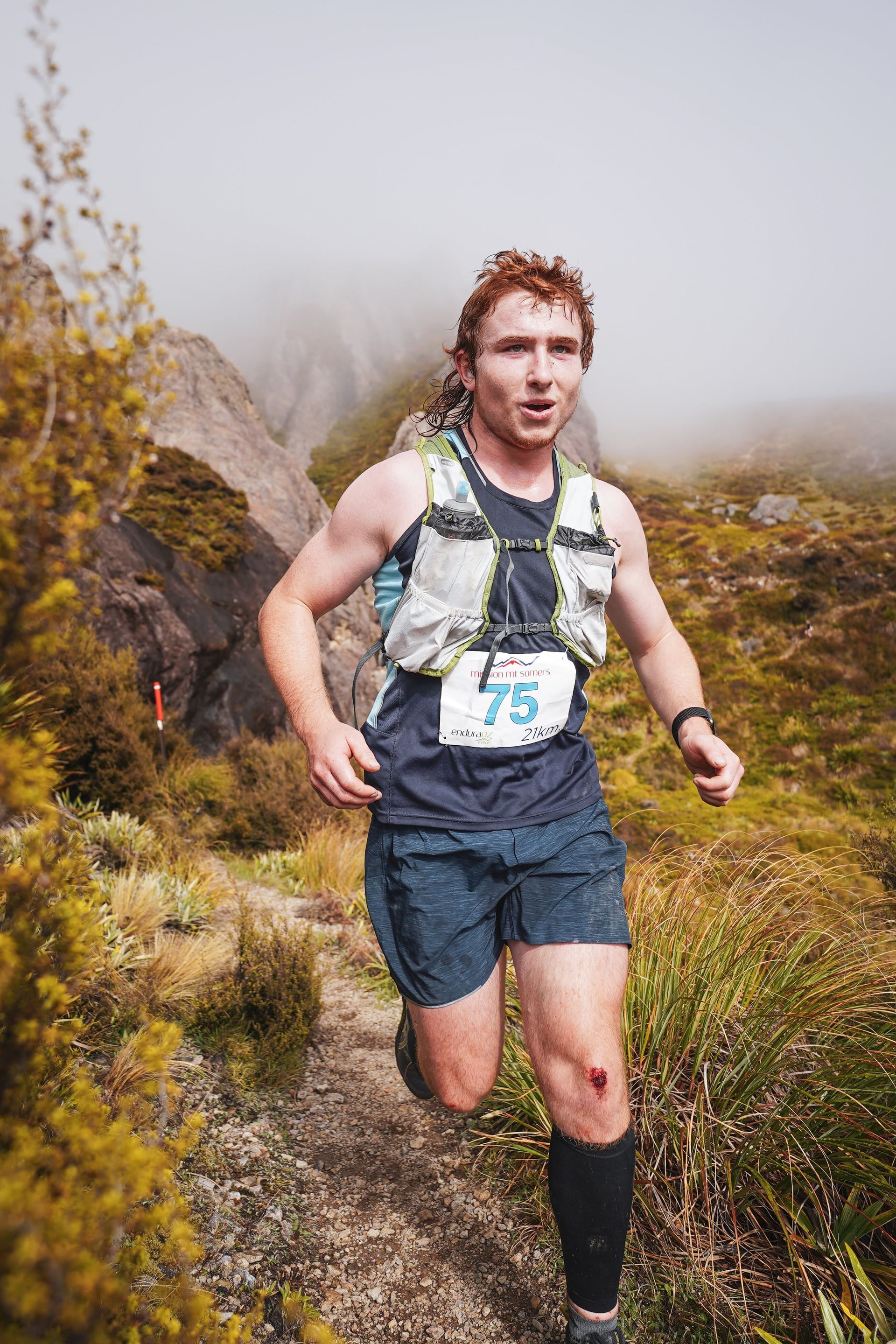 A man is running on a trail in the mountains.