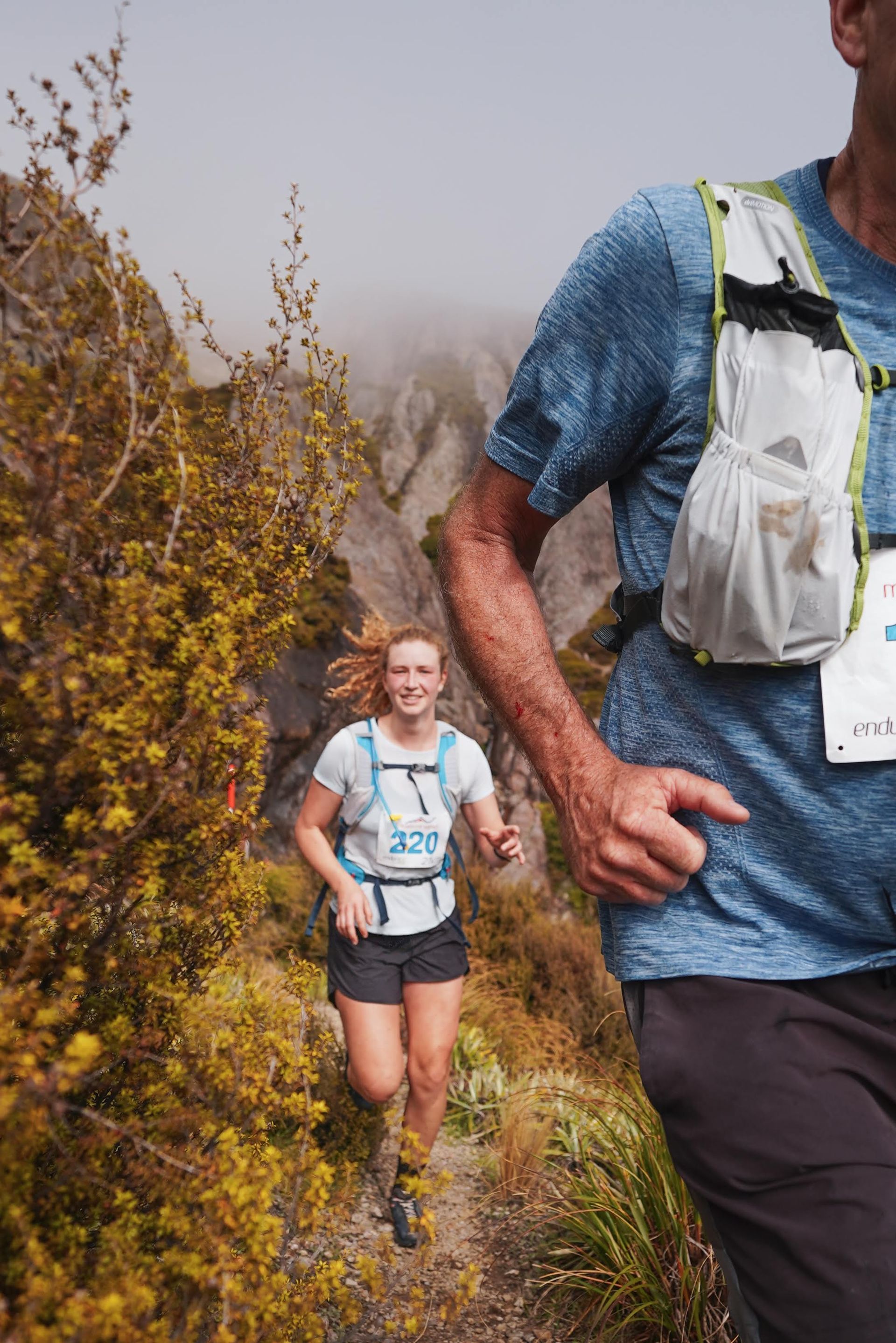 A man and a woman are running on a trail.