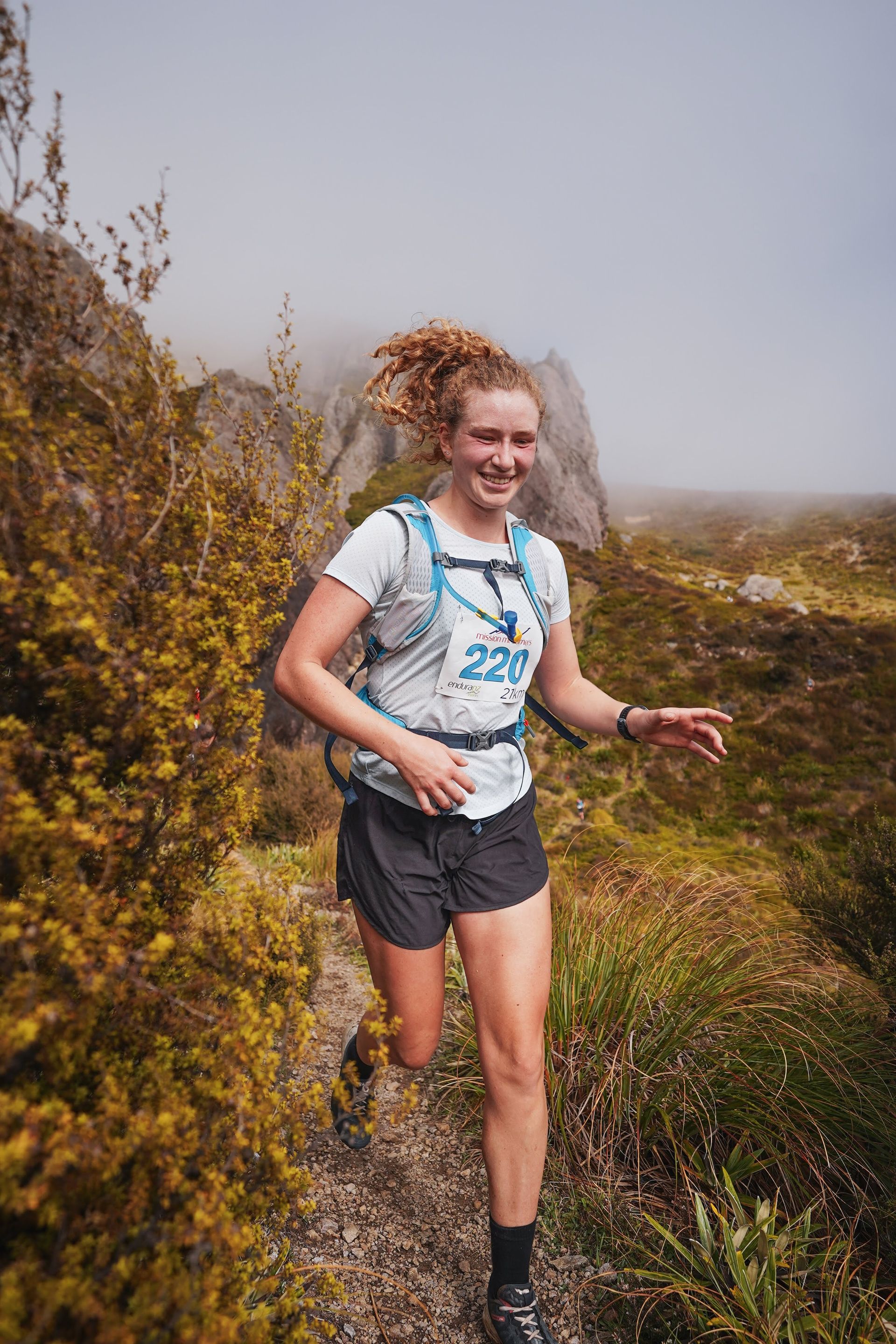 A woman is running on a trail in the mountains.