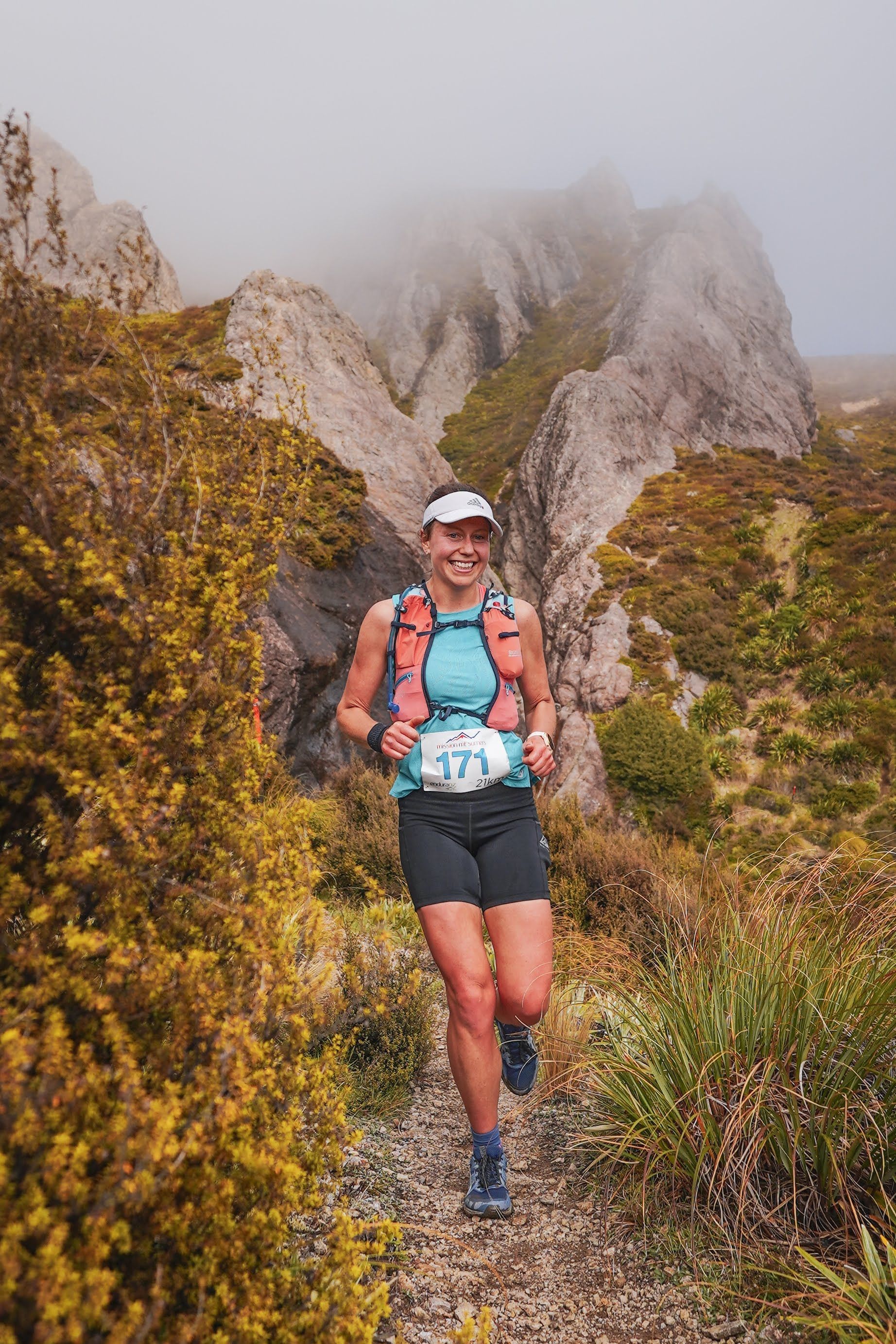 A woman is running on a trail in the mountains.