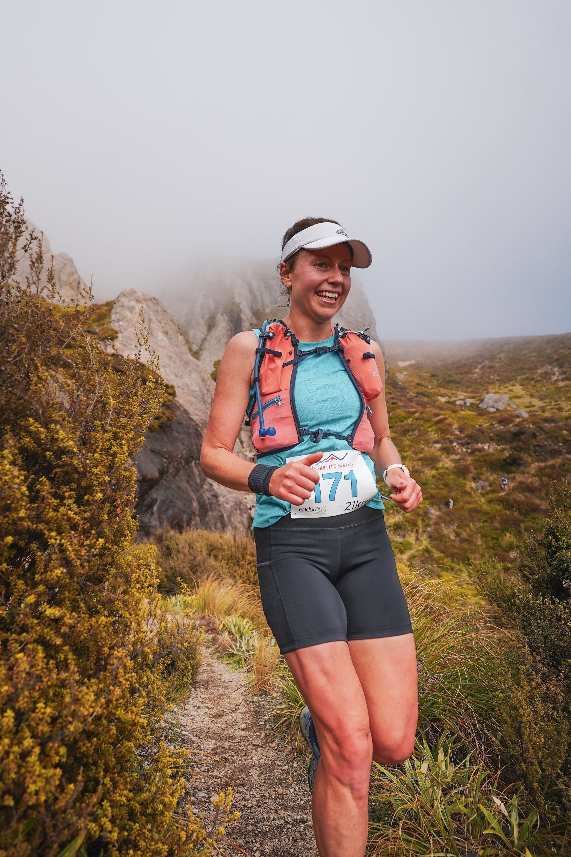 A woman is running on a trail in the mountains.