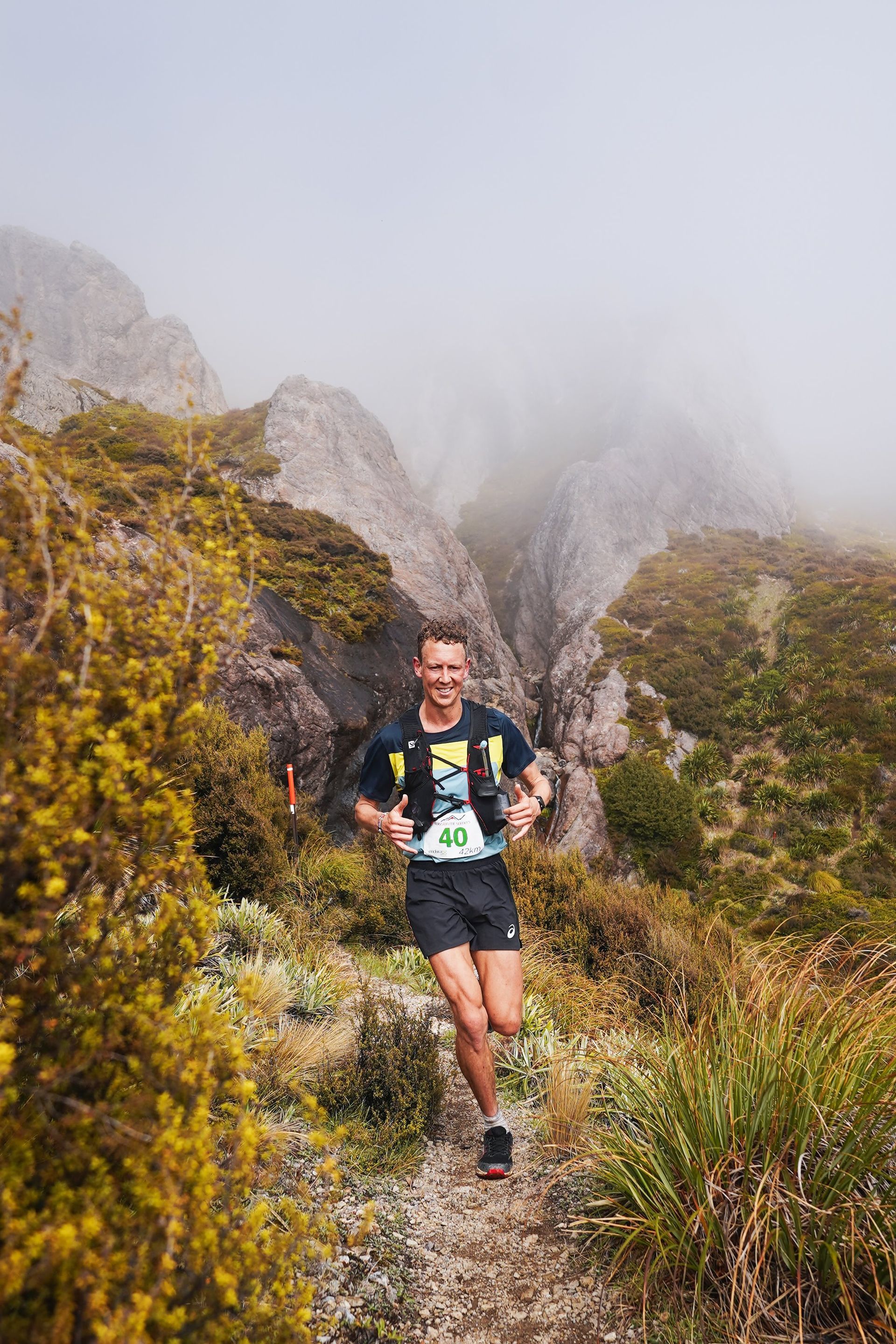 A man is running on a trail in the mountains.