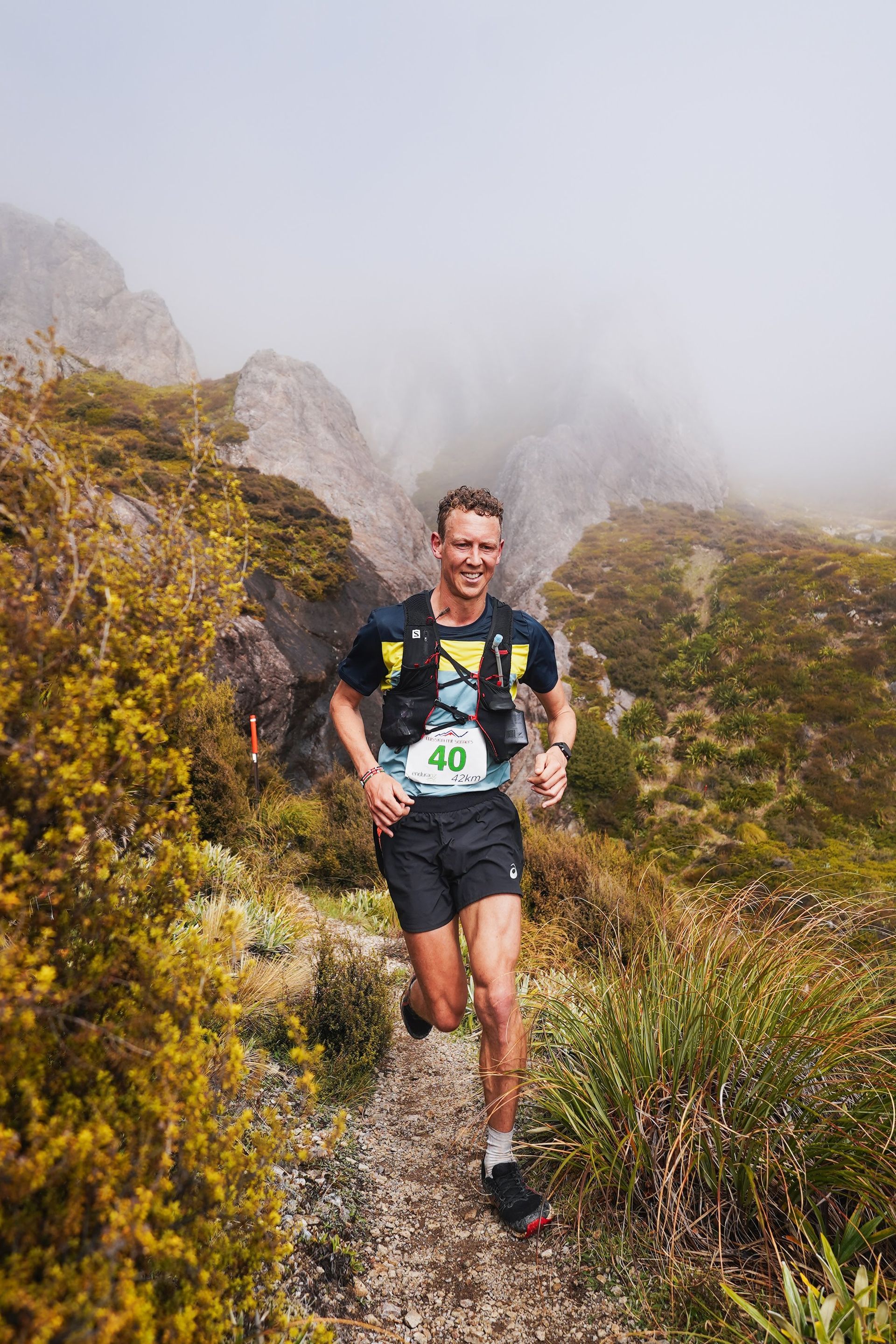 A man is running on a trail in the mountains.
