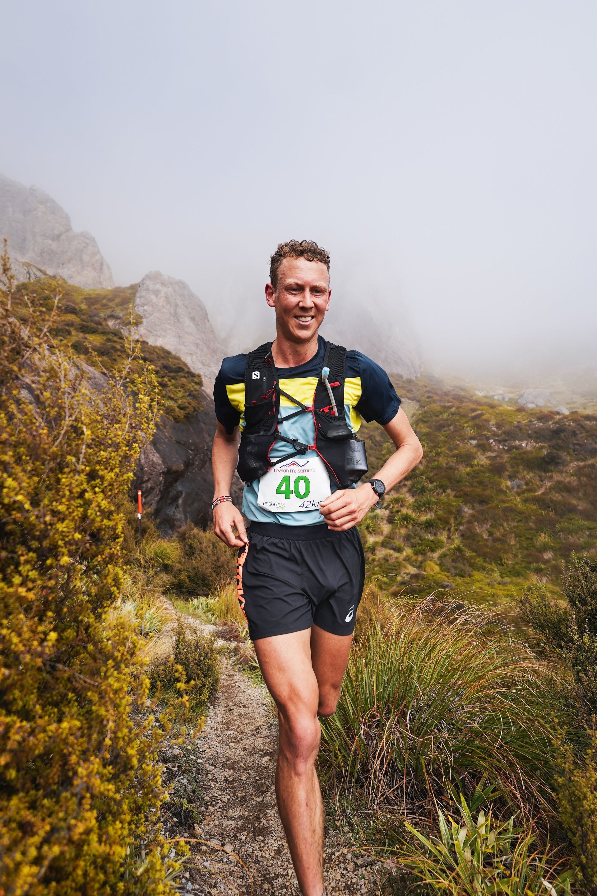A man is running on a trail in the mountains.