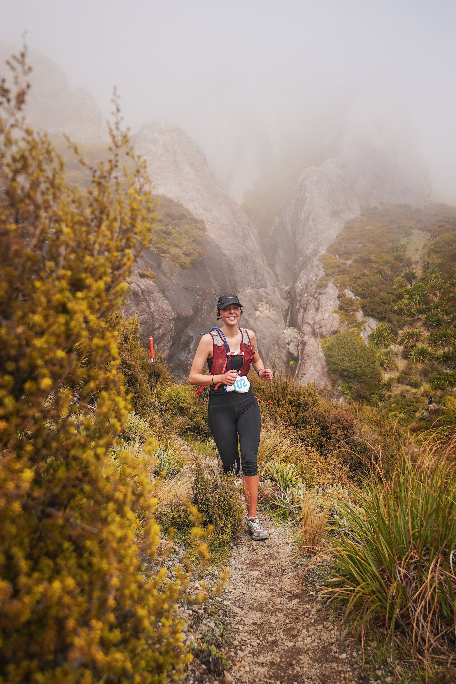 A woman is running on a trail in the mountains.