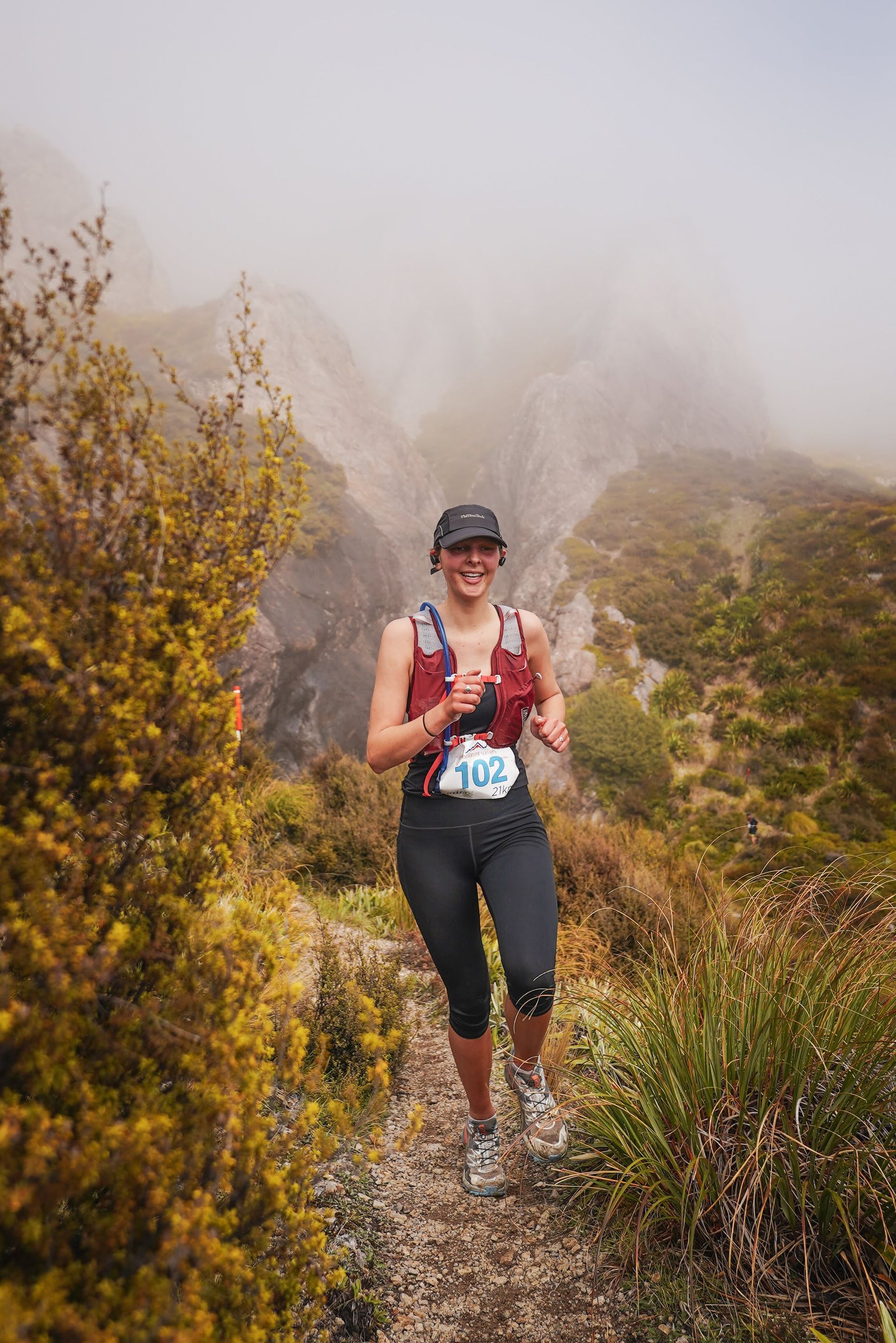 A woman is running on a trail in the mountains.