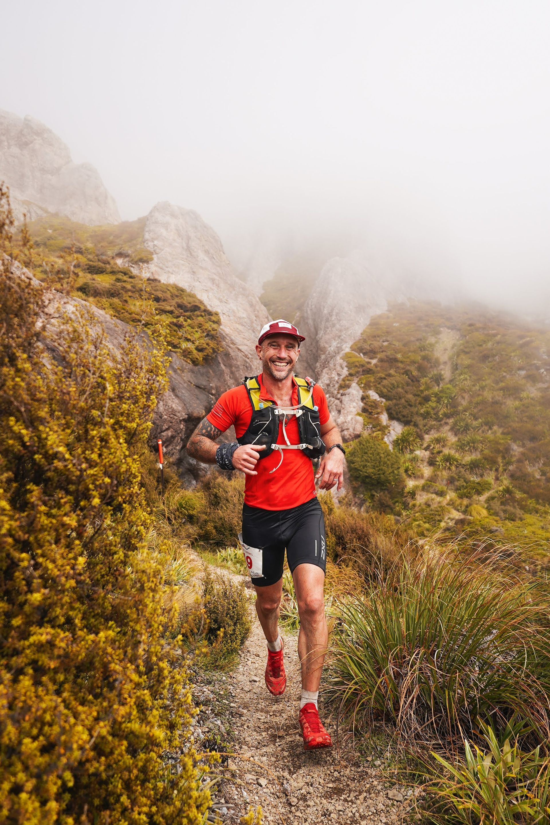 A man is running on a trail in the mountains.