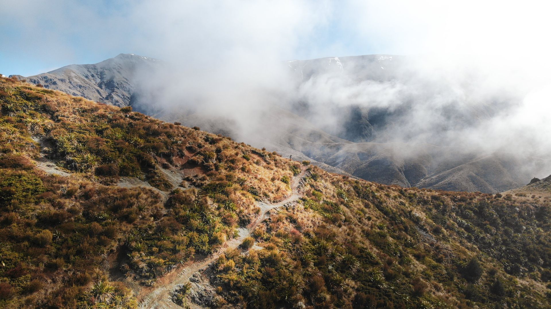 An aerial view of a mountain covered in clouds and trees.