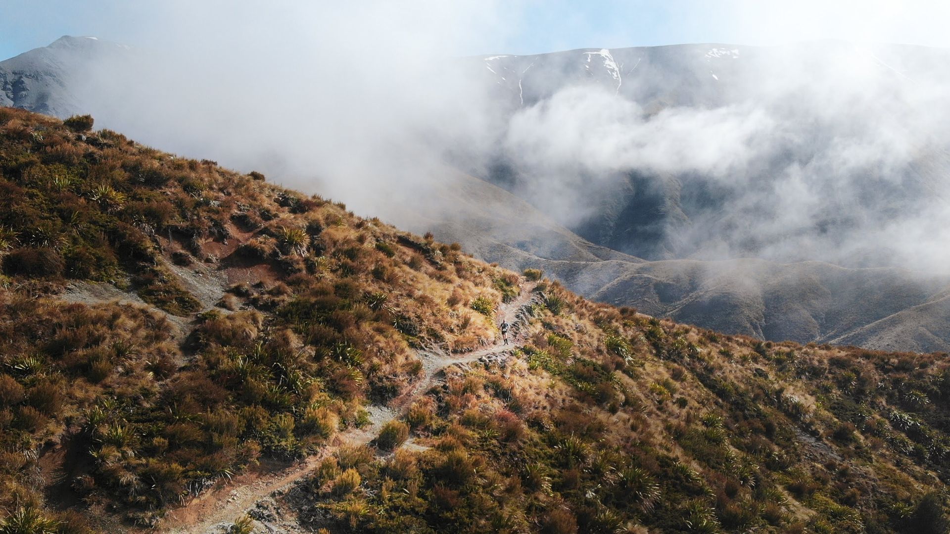 An aerial view of a mountain covered in clouds and trees.