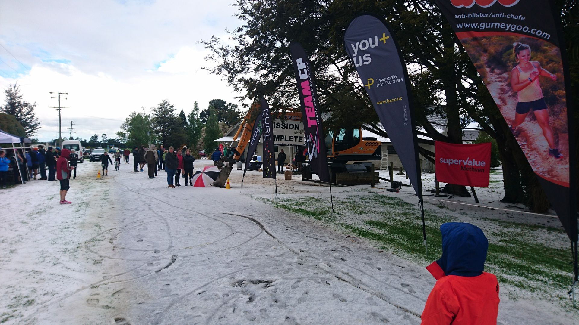 A little boy in a red jacket is standing in the snow.