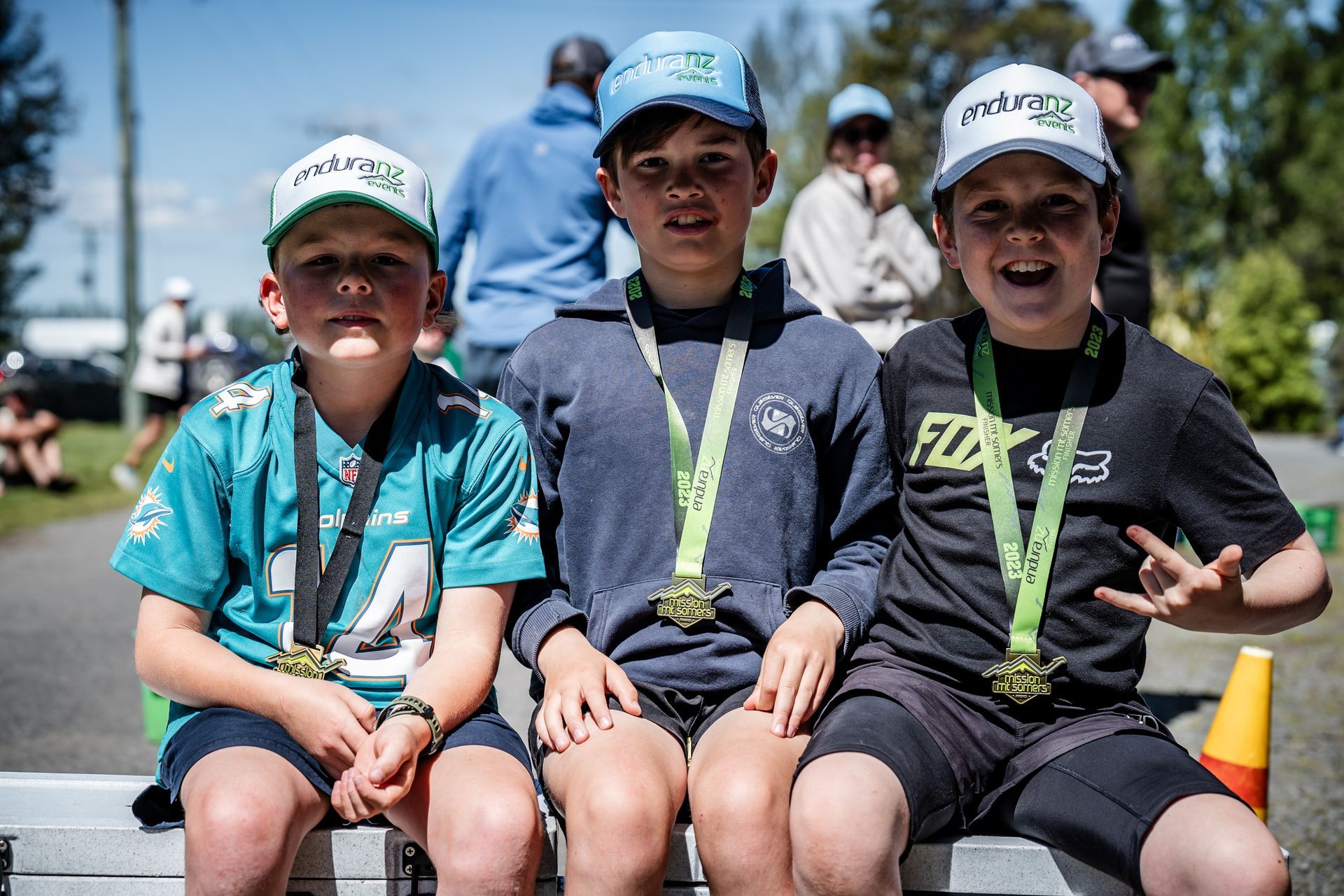 Three young boys wearing medals are sitting on a bench.