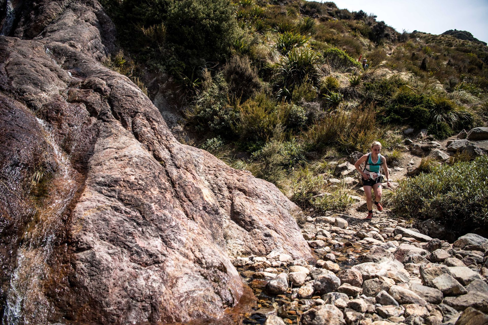 A woman is walking on a rocky trail in the mountains.
