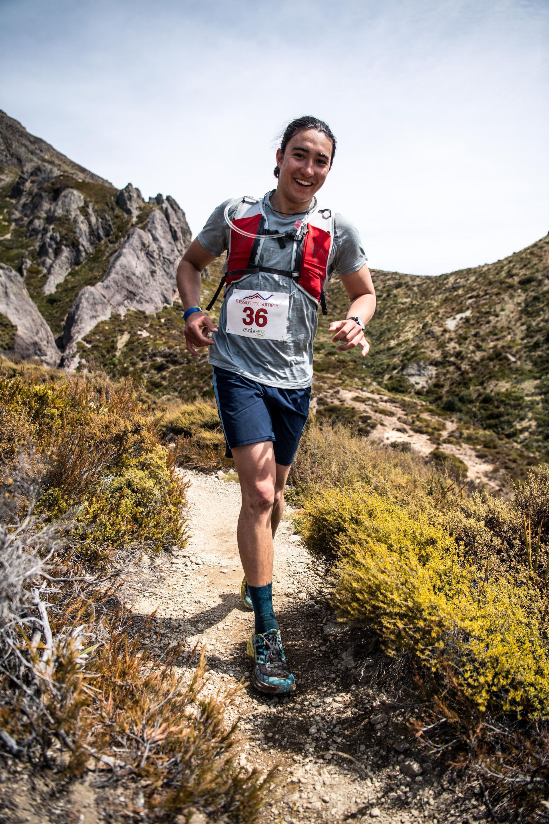 A man is running on a trail in the mountains.