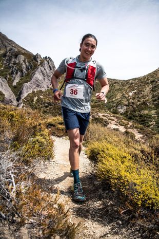 A man is running on a trail in the mountains.