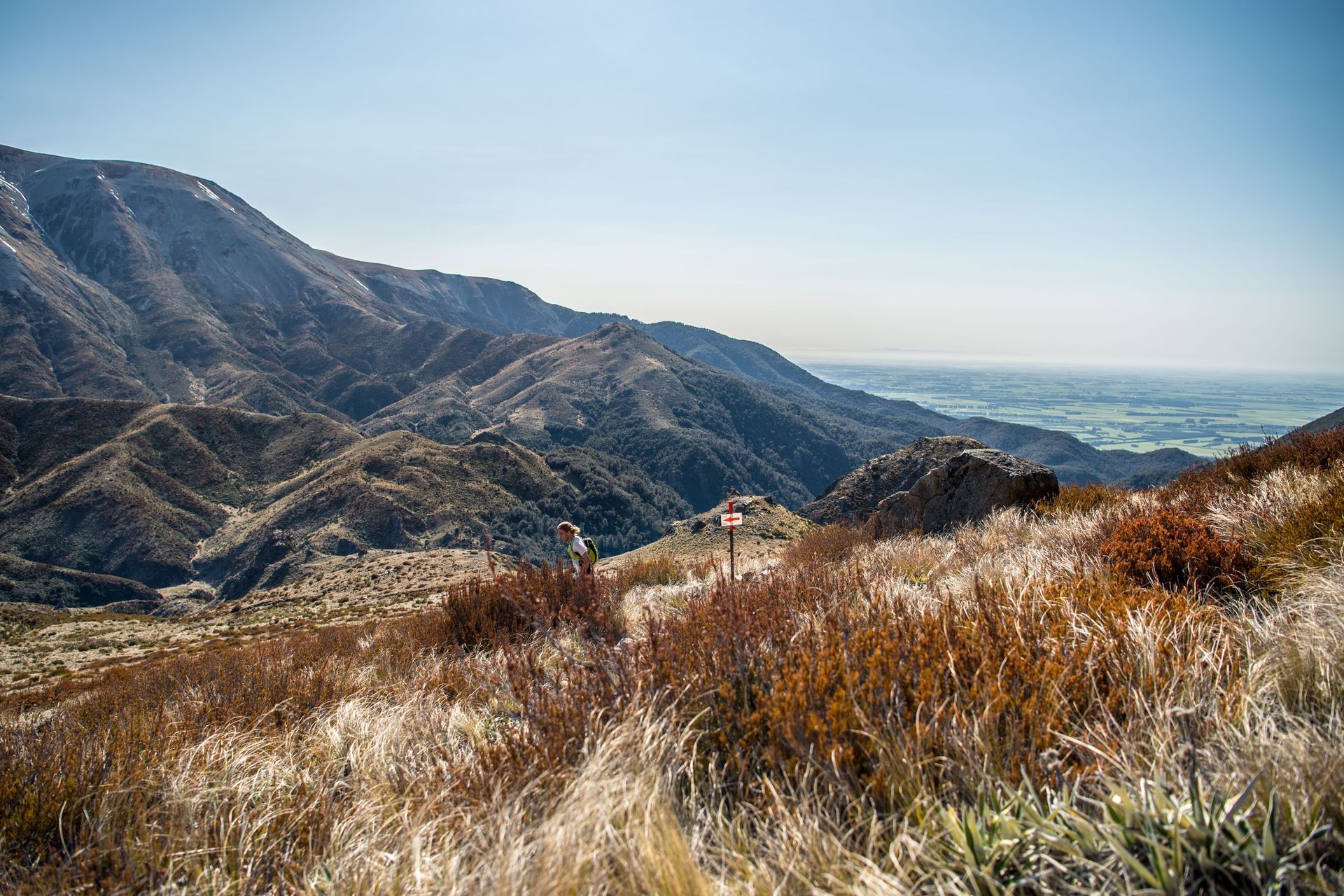 There is a sign in the middle of a field with mountains in the background.