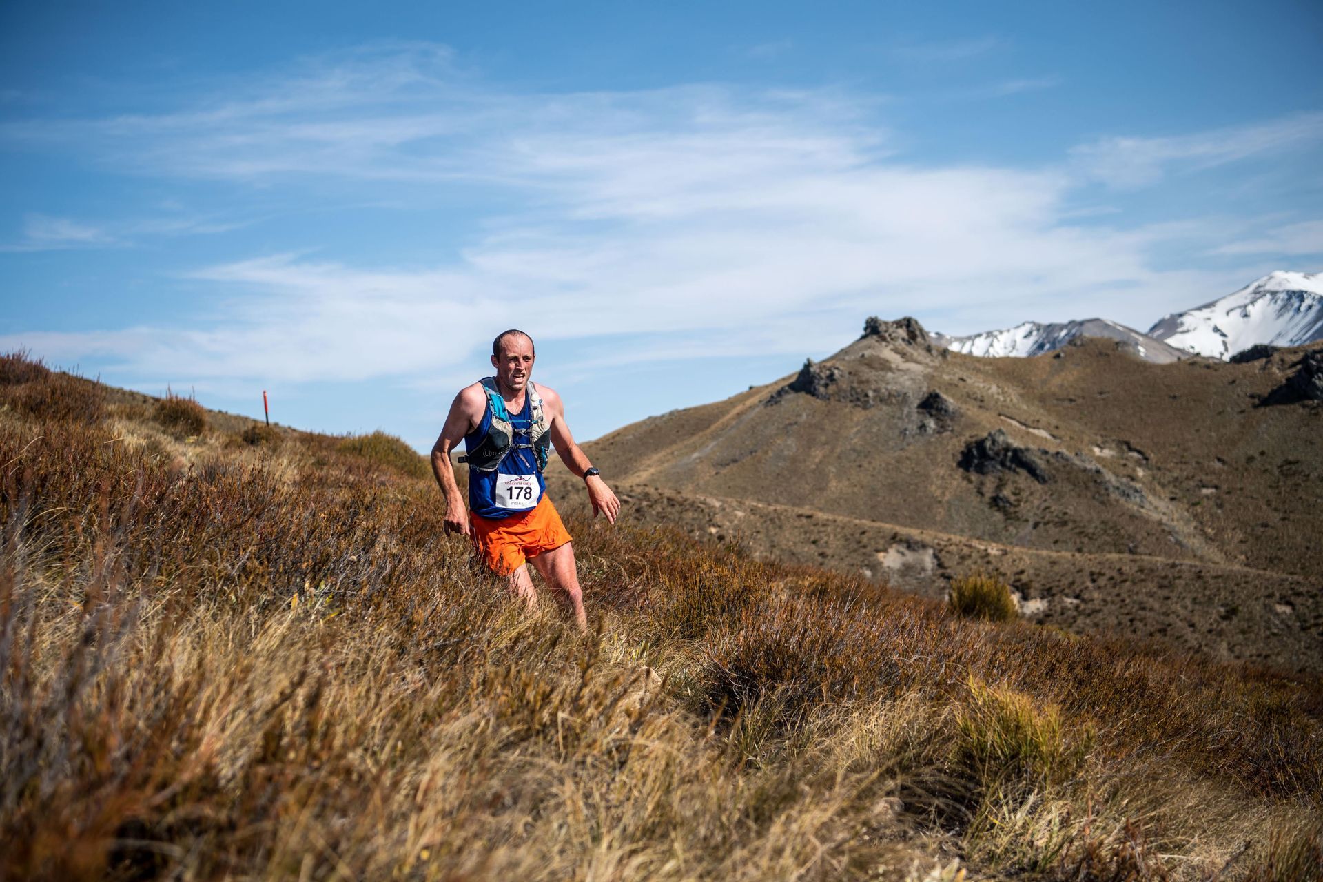 A man is running on a trail in the mountains.