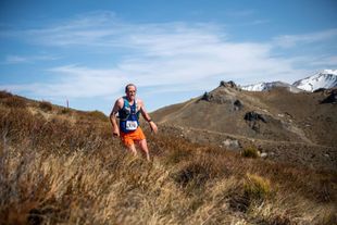 A man is running on a trail in the mountains.