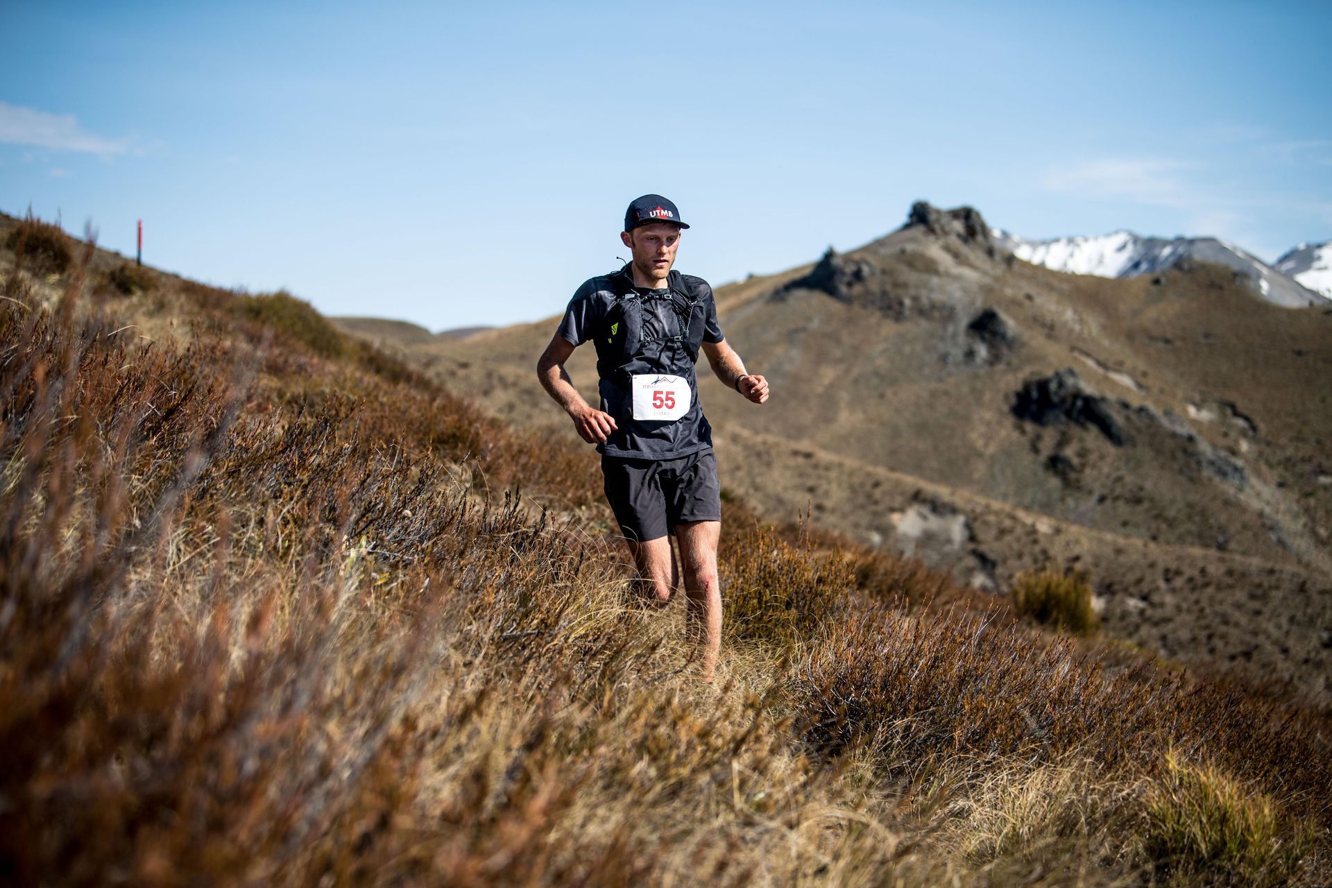 A man is running on a trail in the mountains.