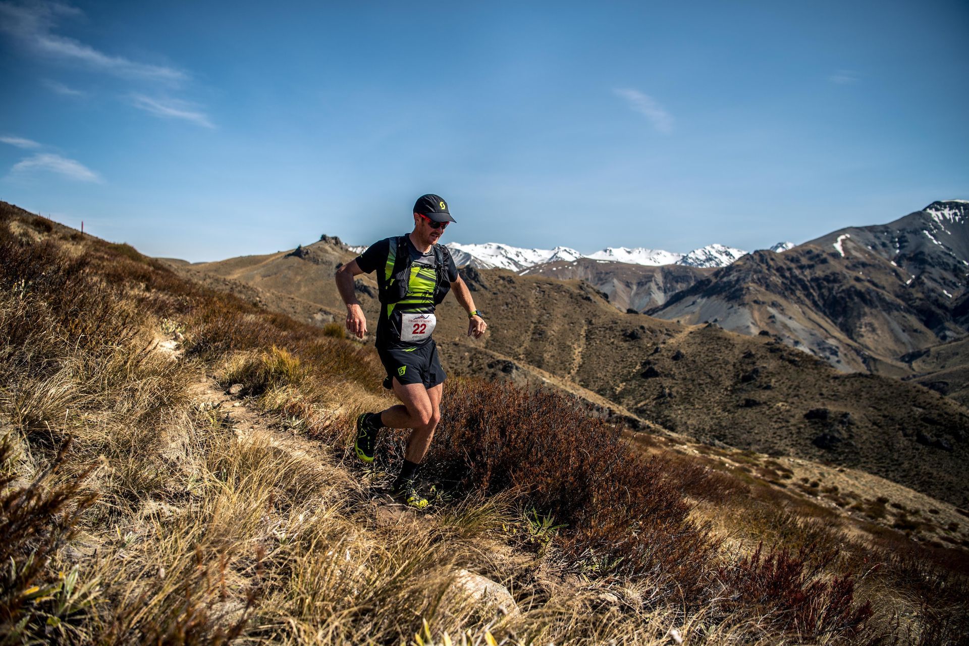 A man is running on a trail in the mountains.