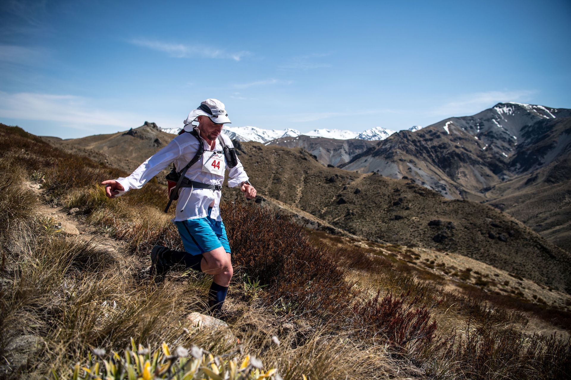 A man is running on a trail in the mountains.