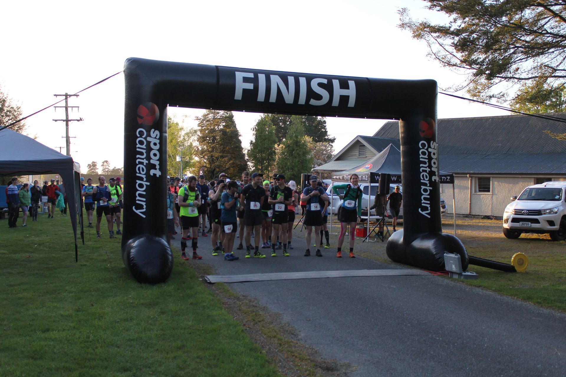 A group of people are standing under an inflatable finish line arch.