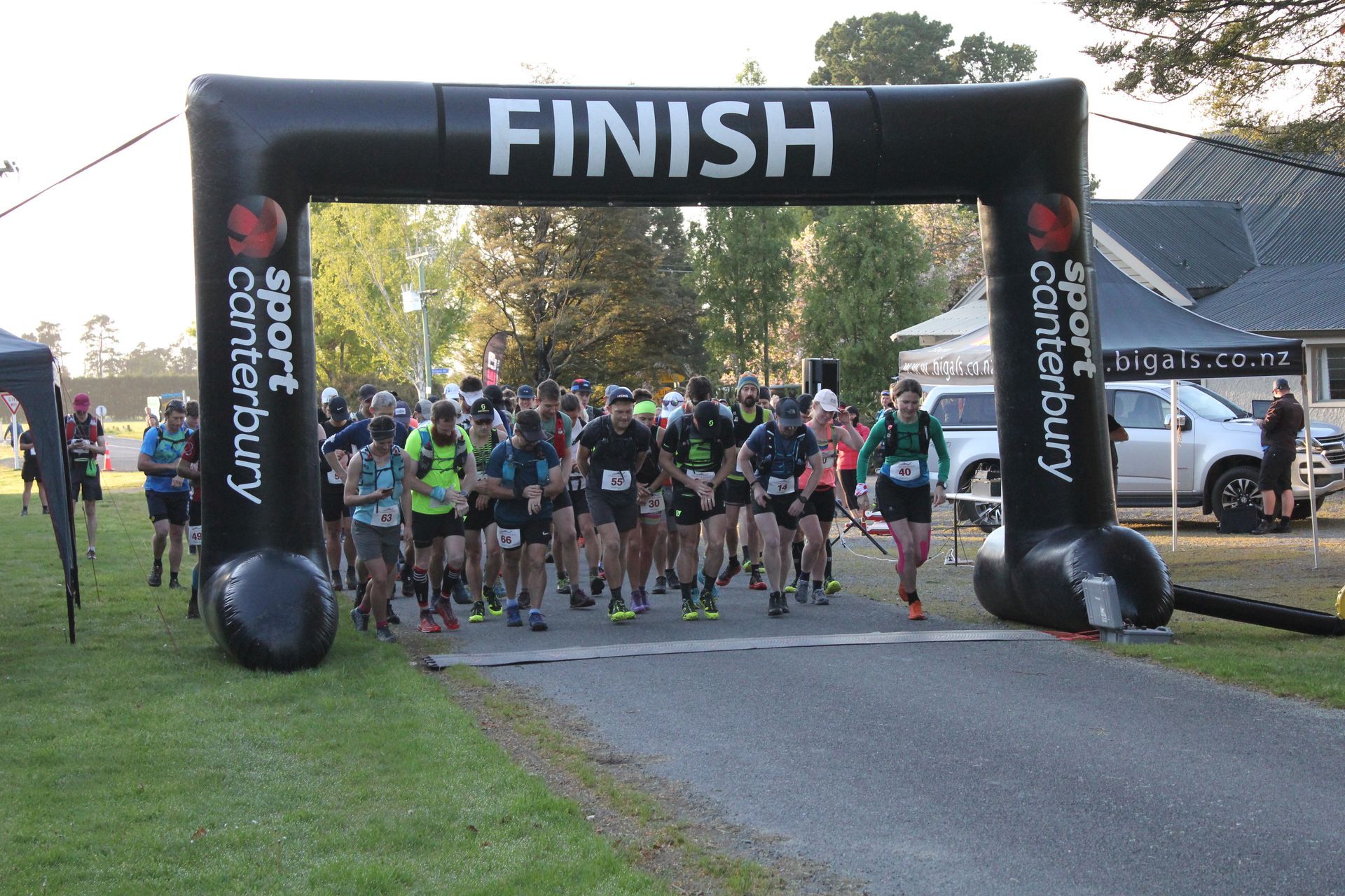 A group of people are starting a race under an inflatable finish sign.