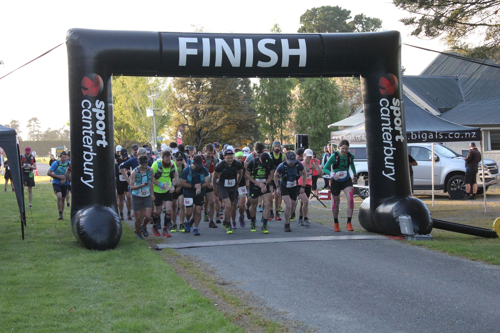 A group of people are running a race under an inflatable finish arch.