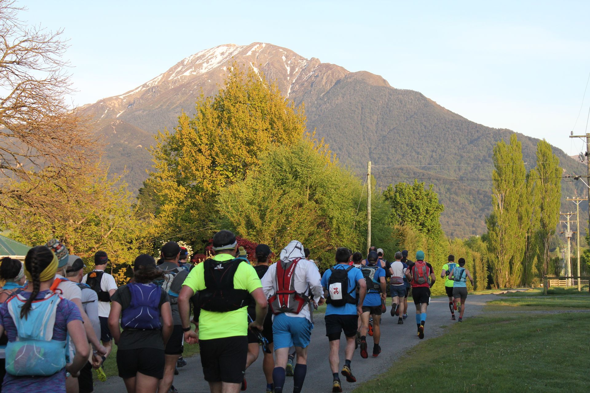 A group of people are running down a path with a mountain in the background.