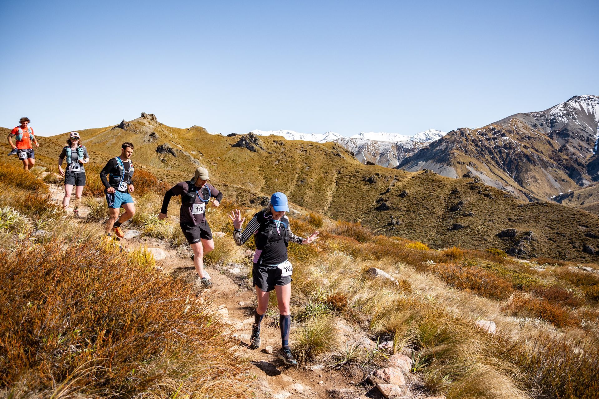 A group of people are running on a trail in the mountains.