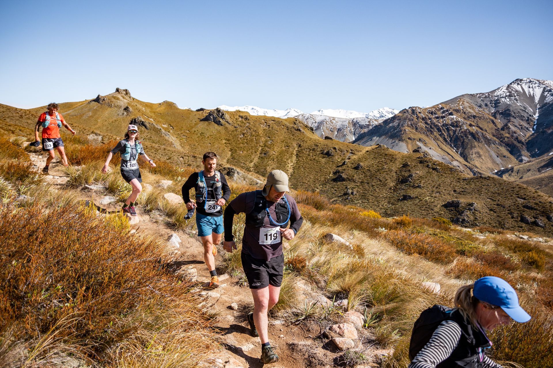 A group of people are running up a mountain trail.