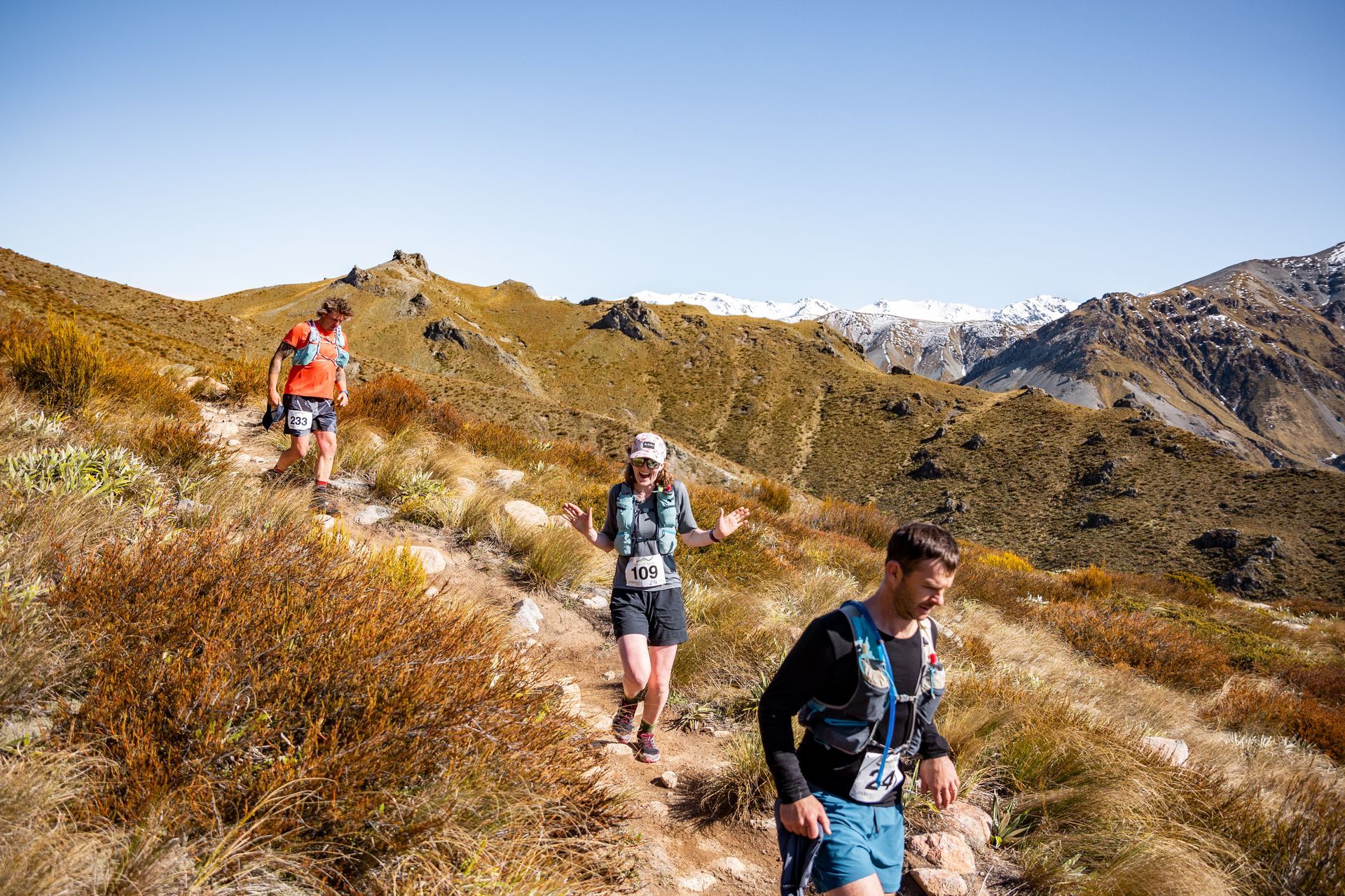 A group of people are running on a trail in the mountains.