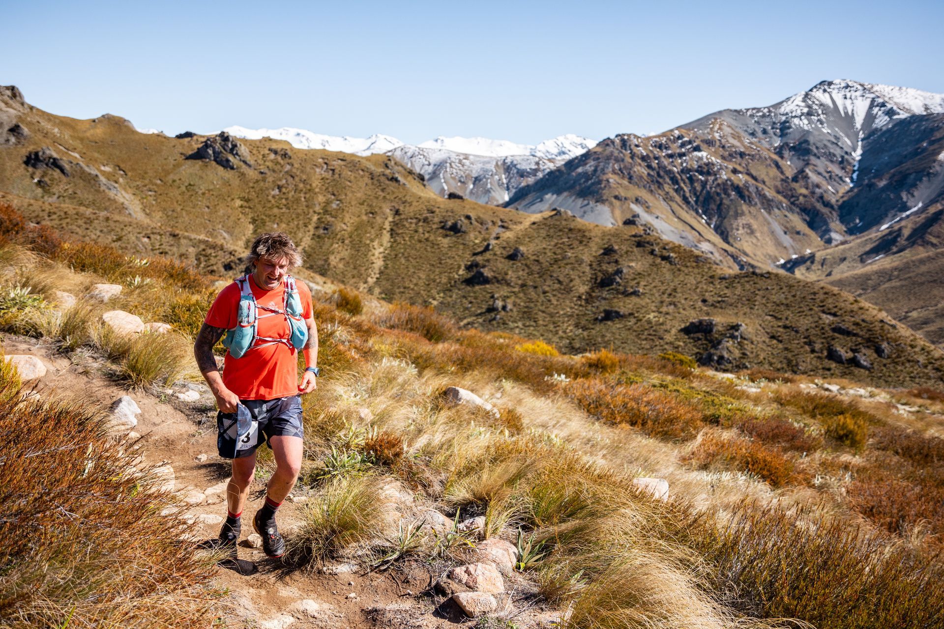 A man is running on a trail in the mountains.