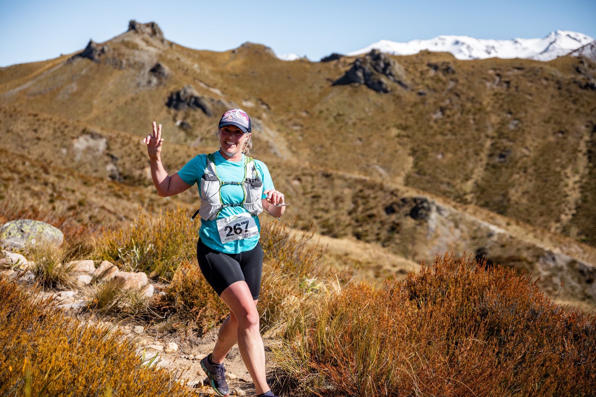 A woman is running on a trail in the mountains.
