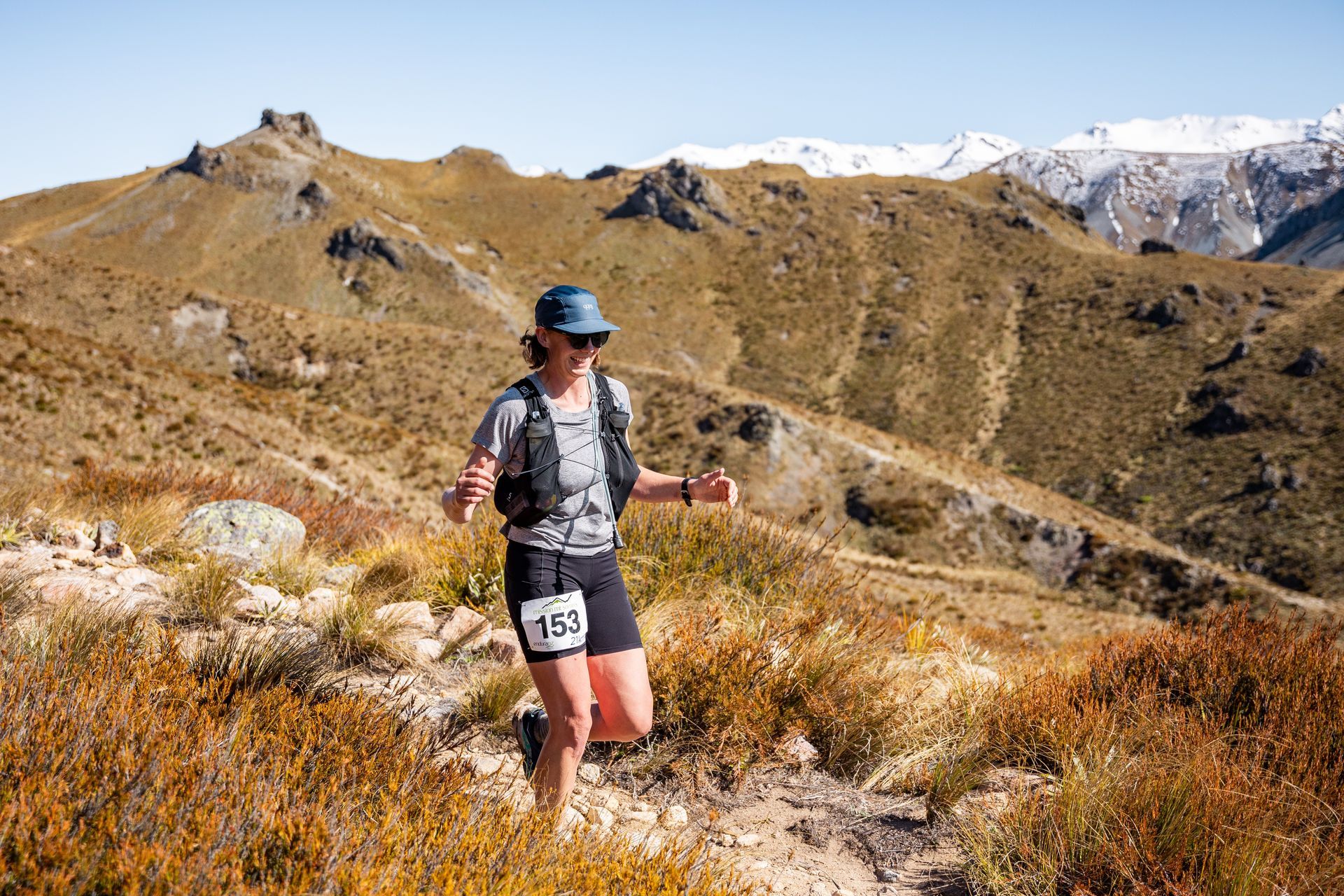 A woman is running on a trail in the mountains.