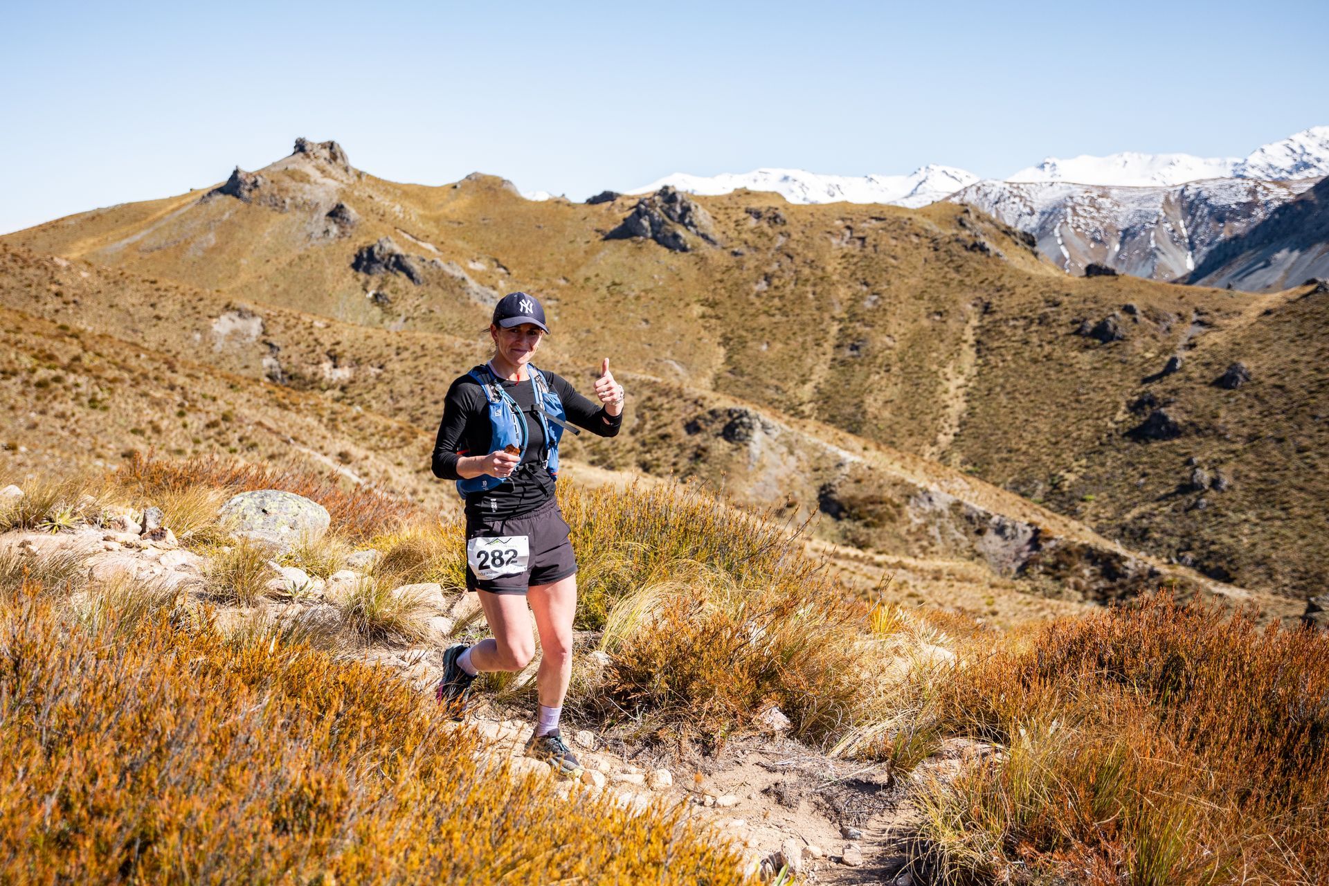 A man is running on a trail in the mountains.