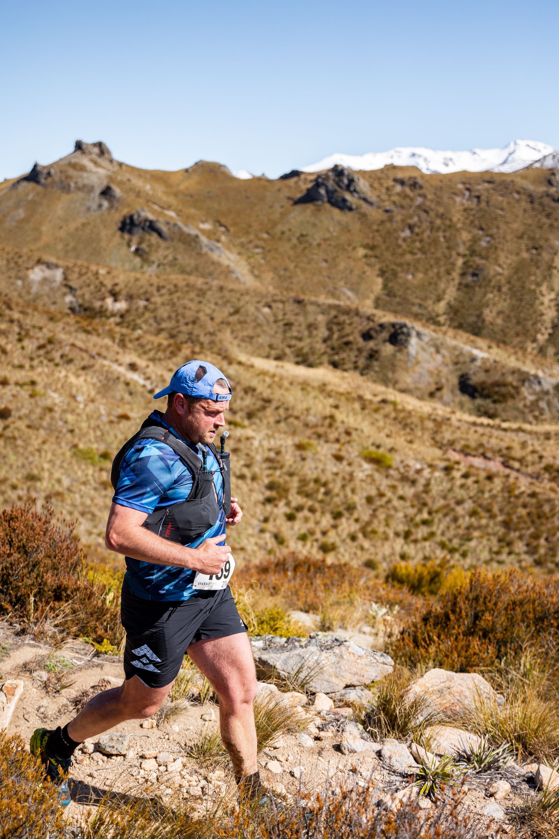 A man is running on a trail in the mountains.