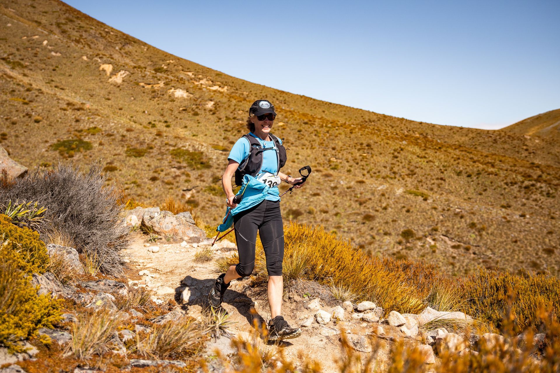 A woman is walking a dog on a trail in the desert.
