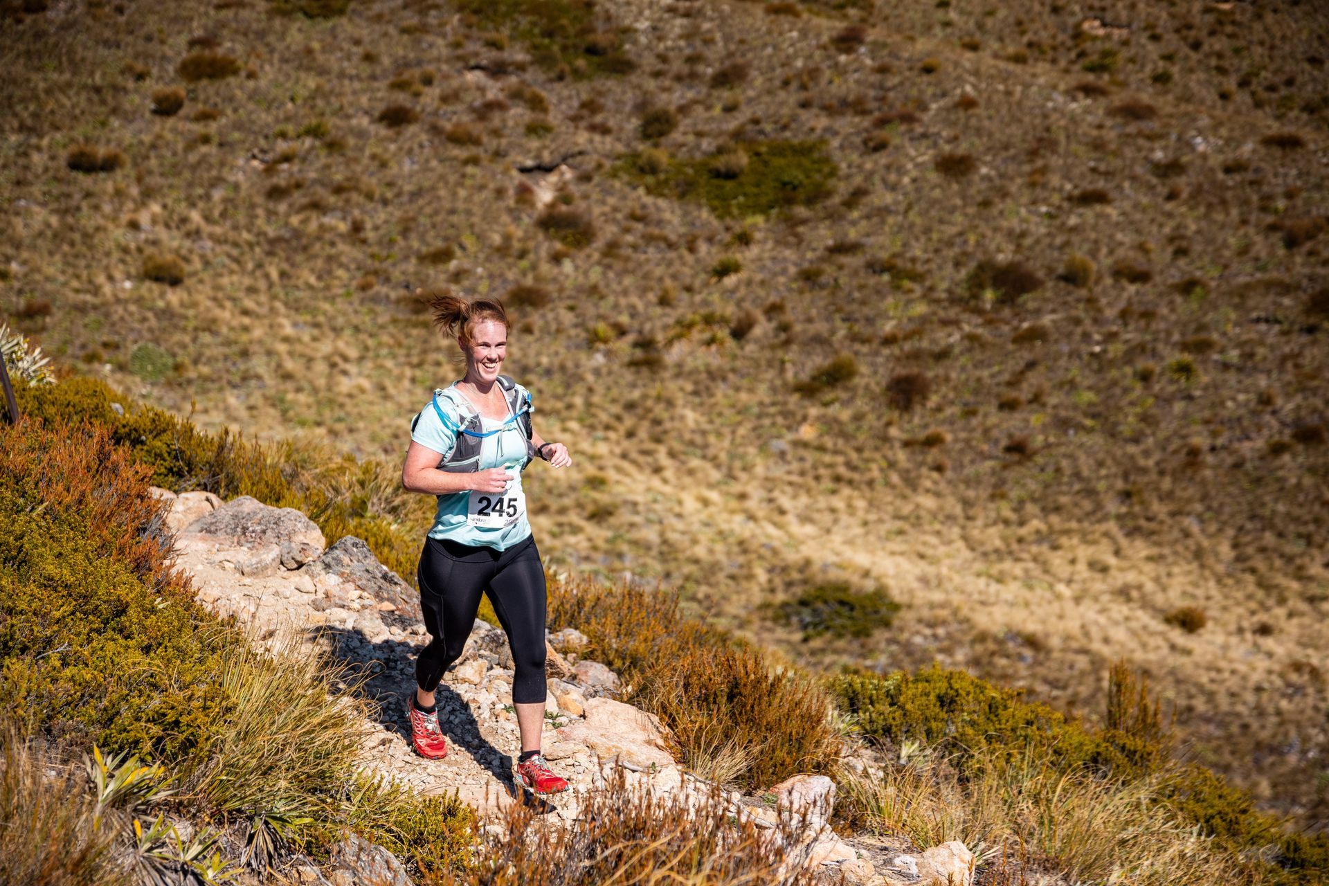 A woman is running up a hill in the desert.