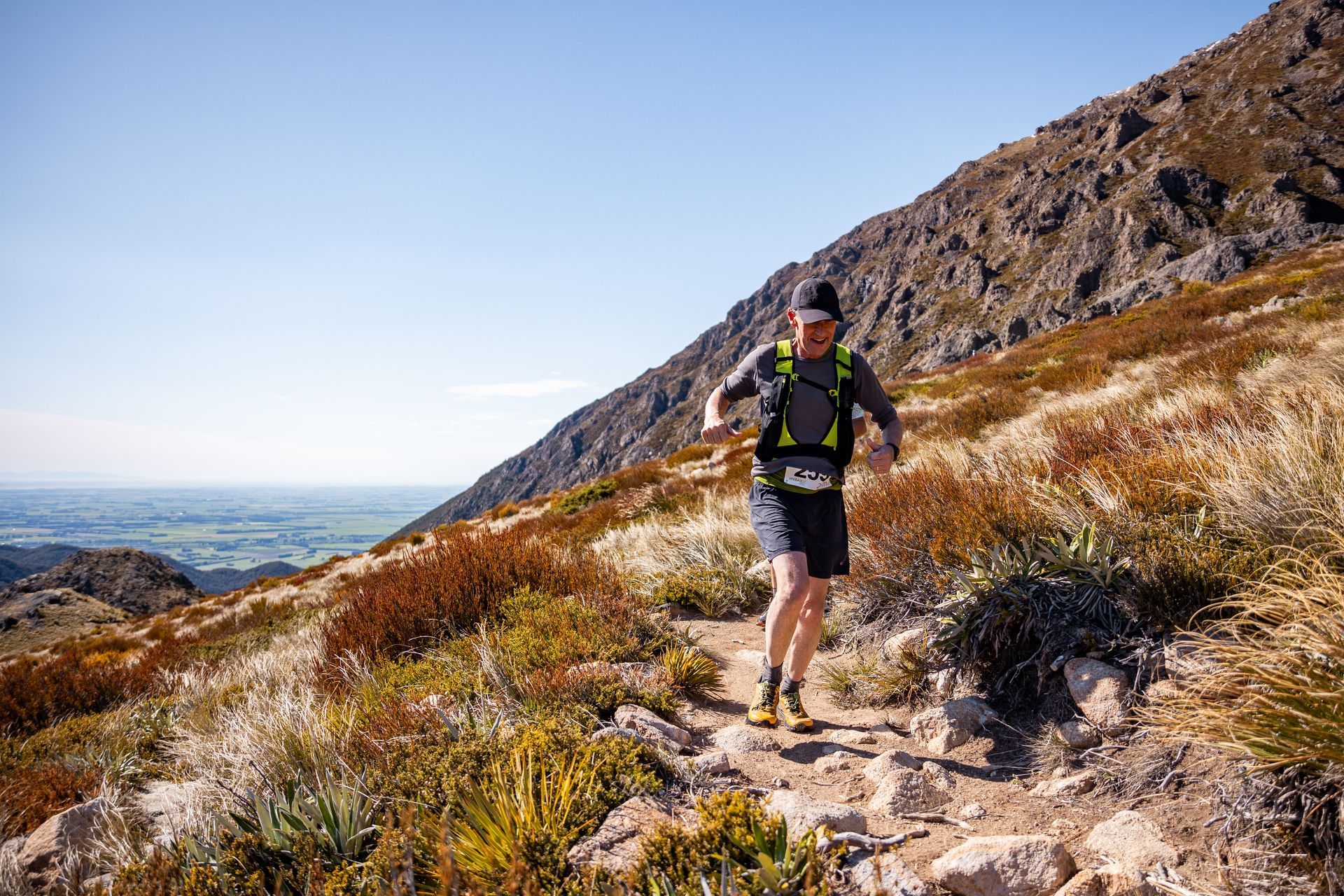 A man is running up a hill on a trail.