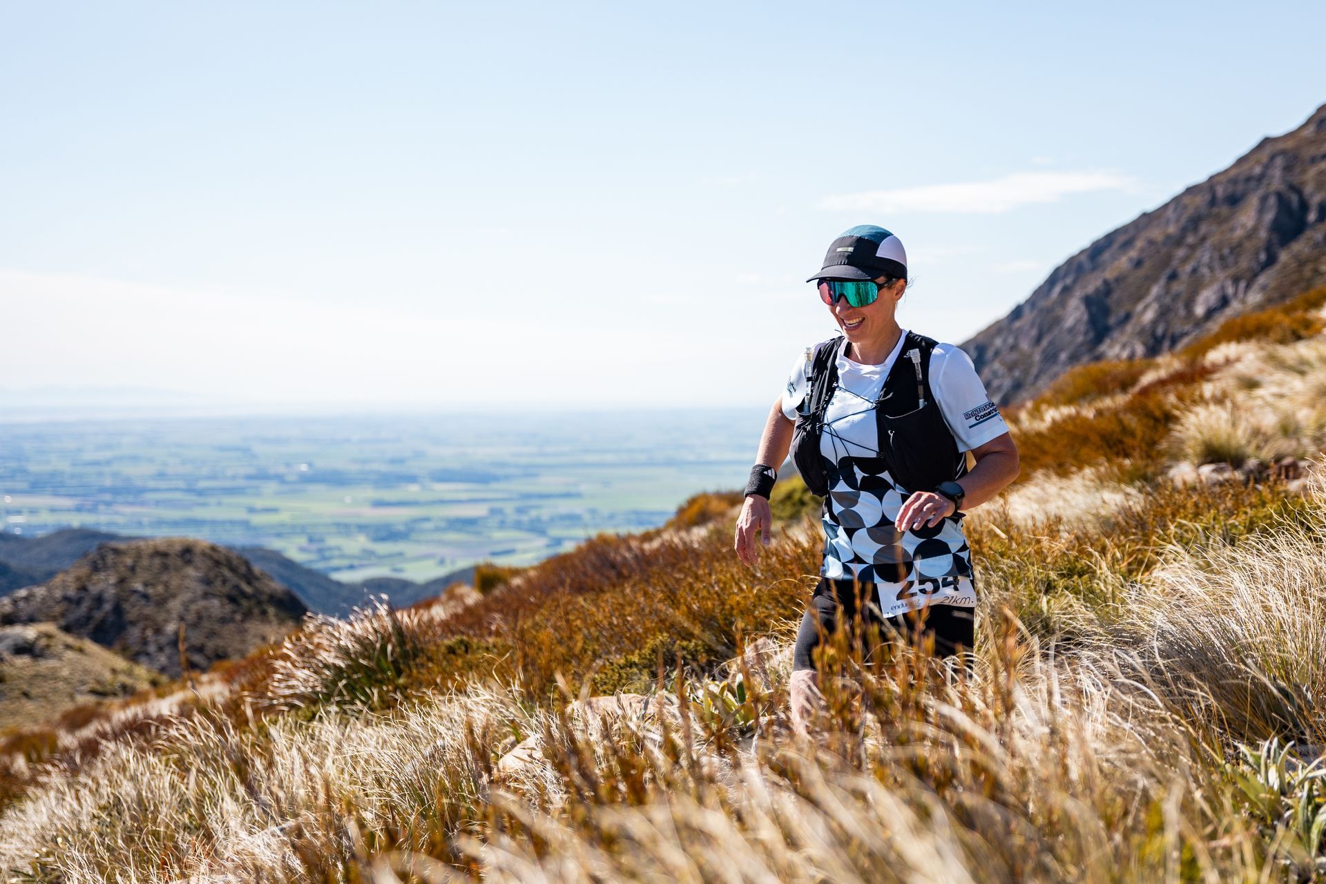 A woman is running on a trail in the mountains.