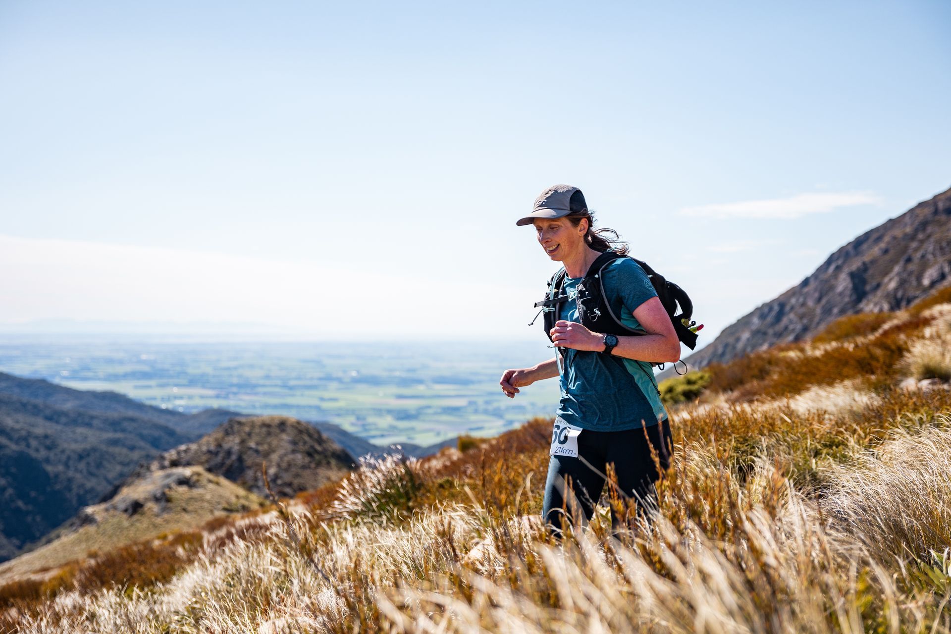 A woman with a backpack is running up a hill.