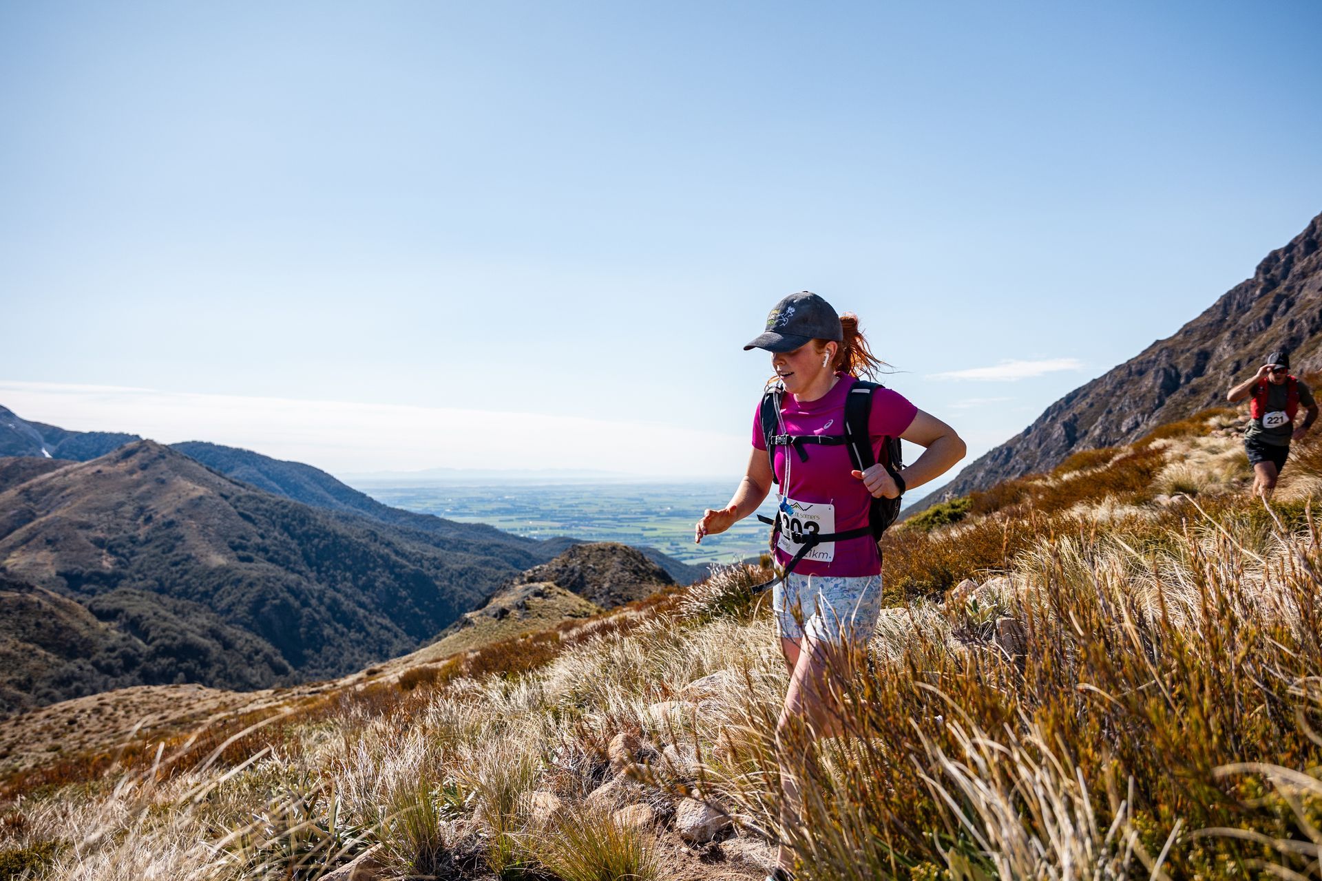 A woman is running on a trail in the mountains.