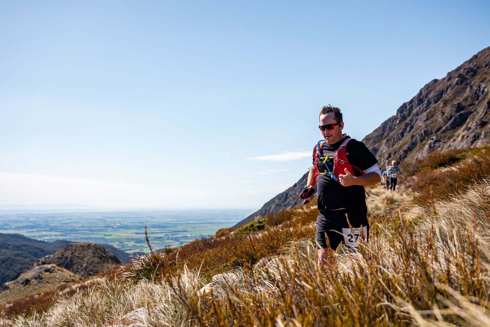 A man is running on a trail in the mountains.