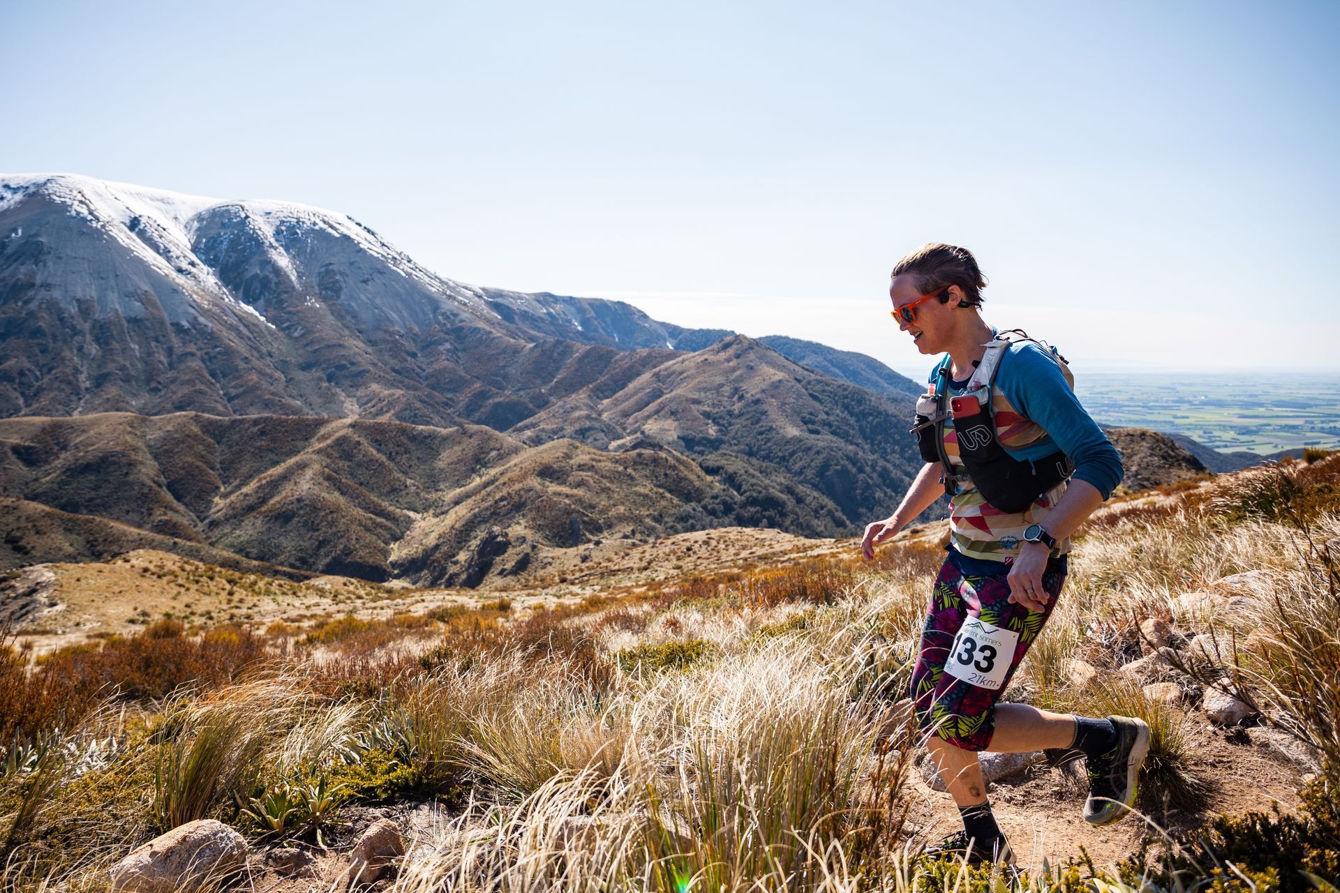 A man is running on a trail in the mountains.