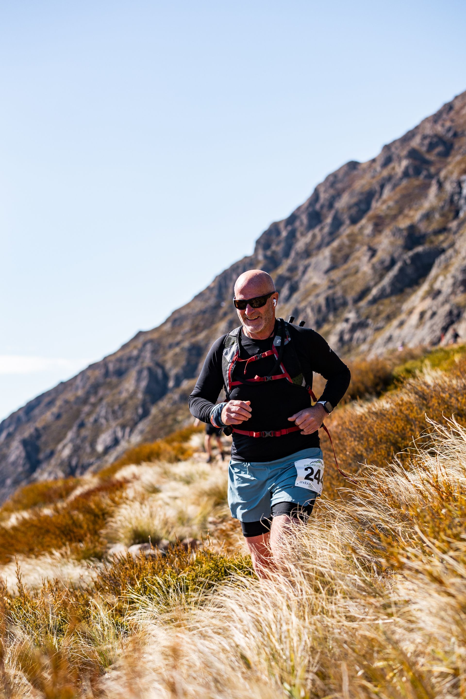 A man is running on a trail in the mountains.