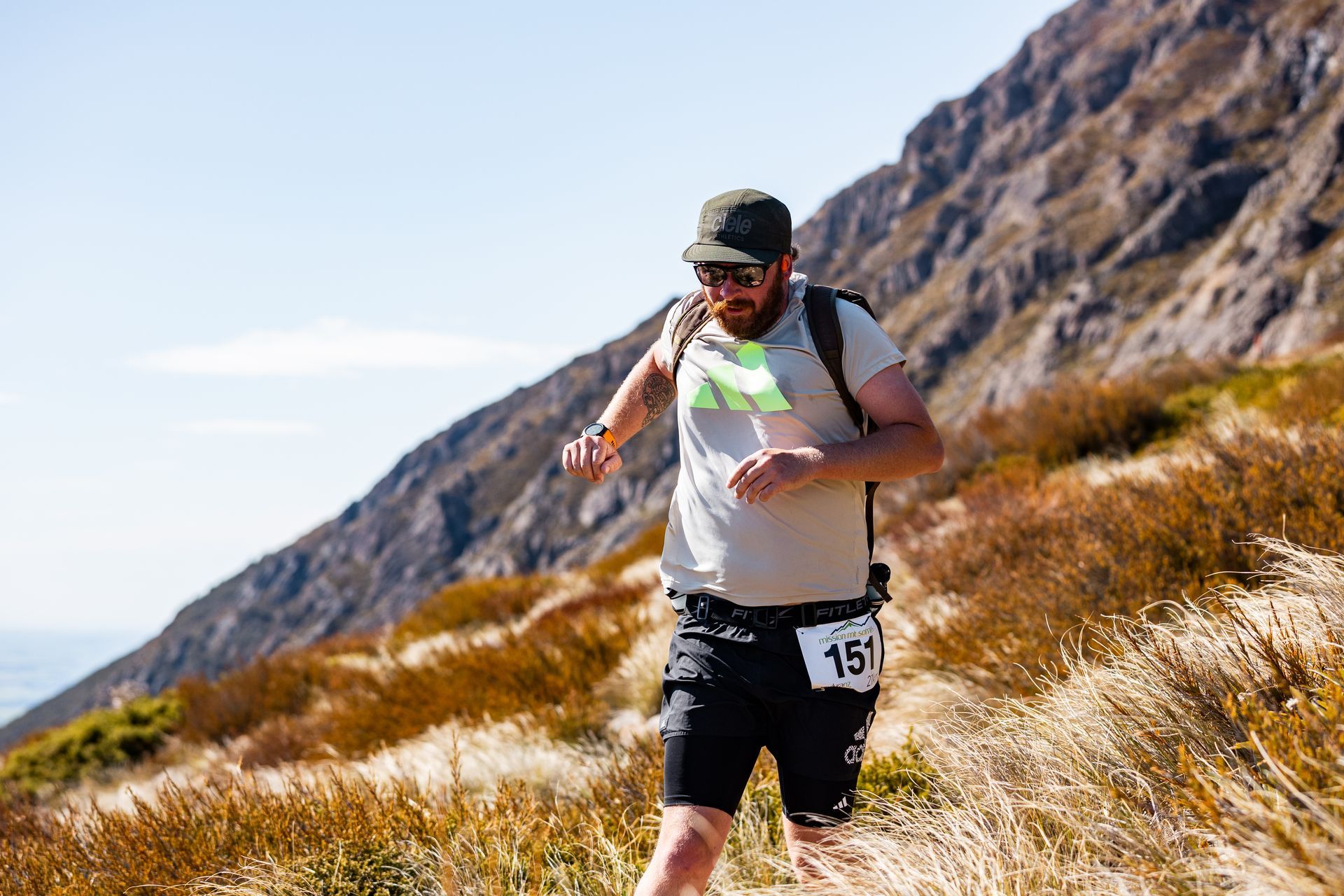 A man is running on a trail in the mountains.