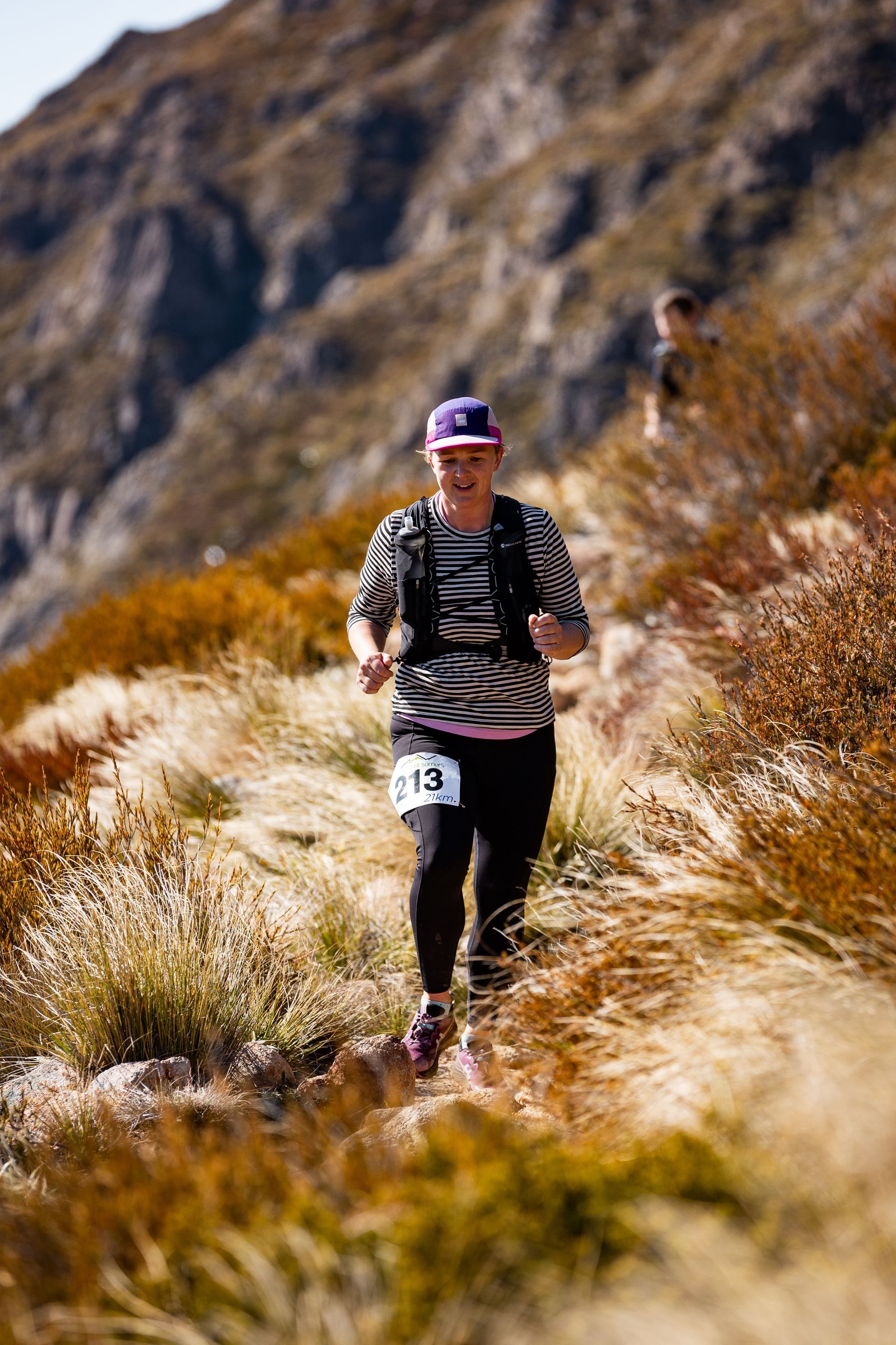 A woman is running on a trail in the mountains.