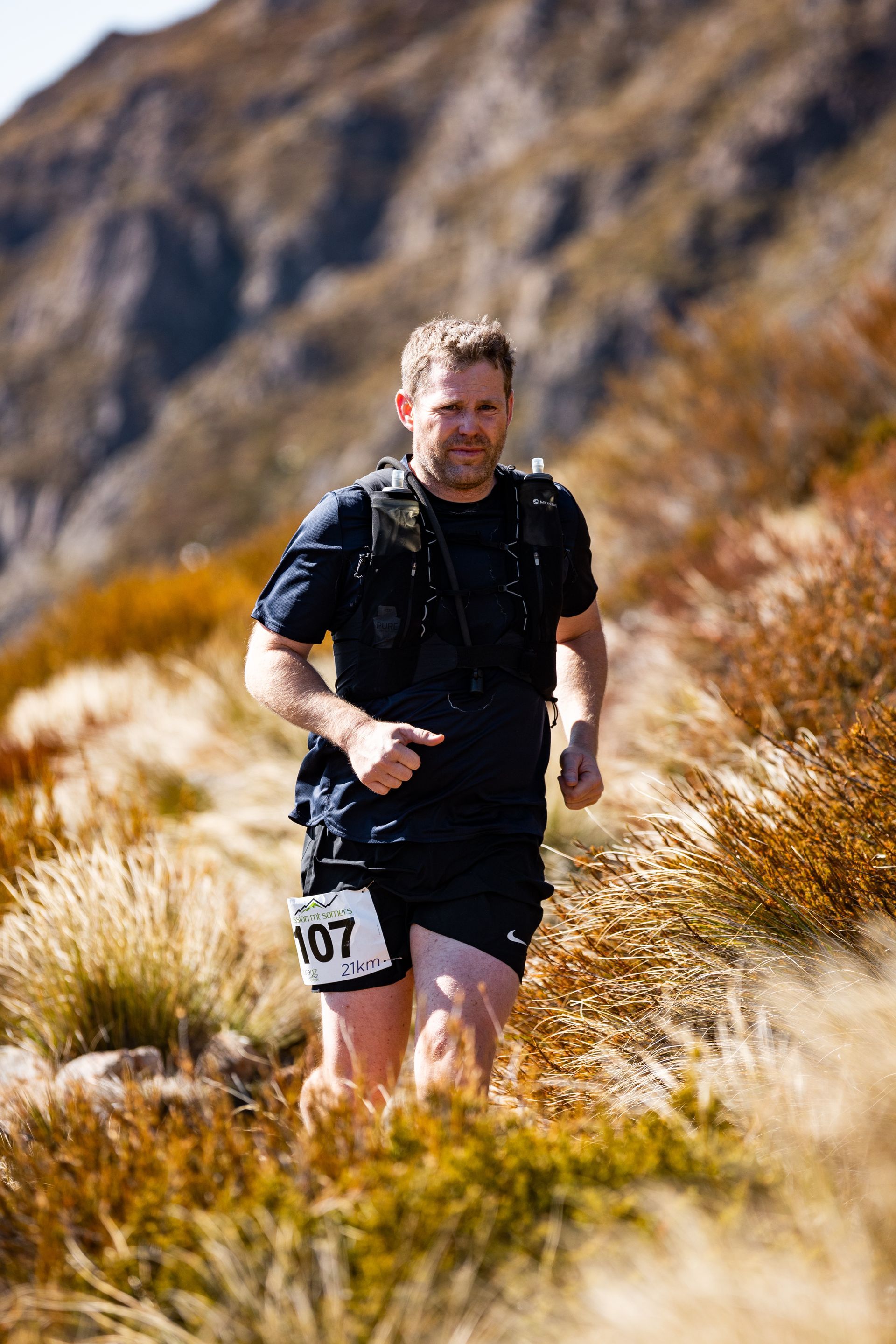 A man is running on a trail in the mountains.