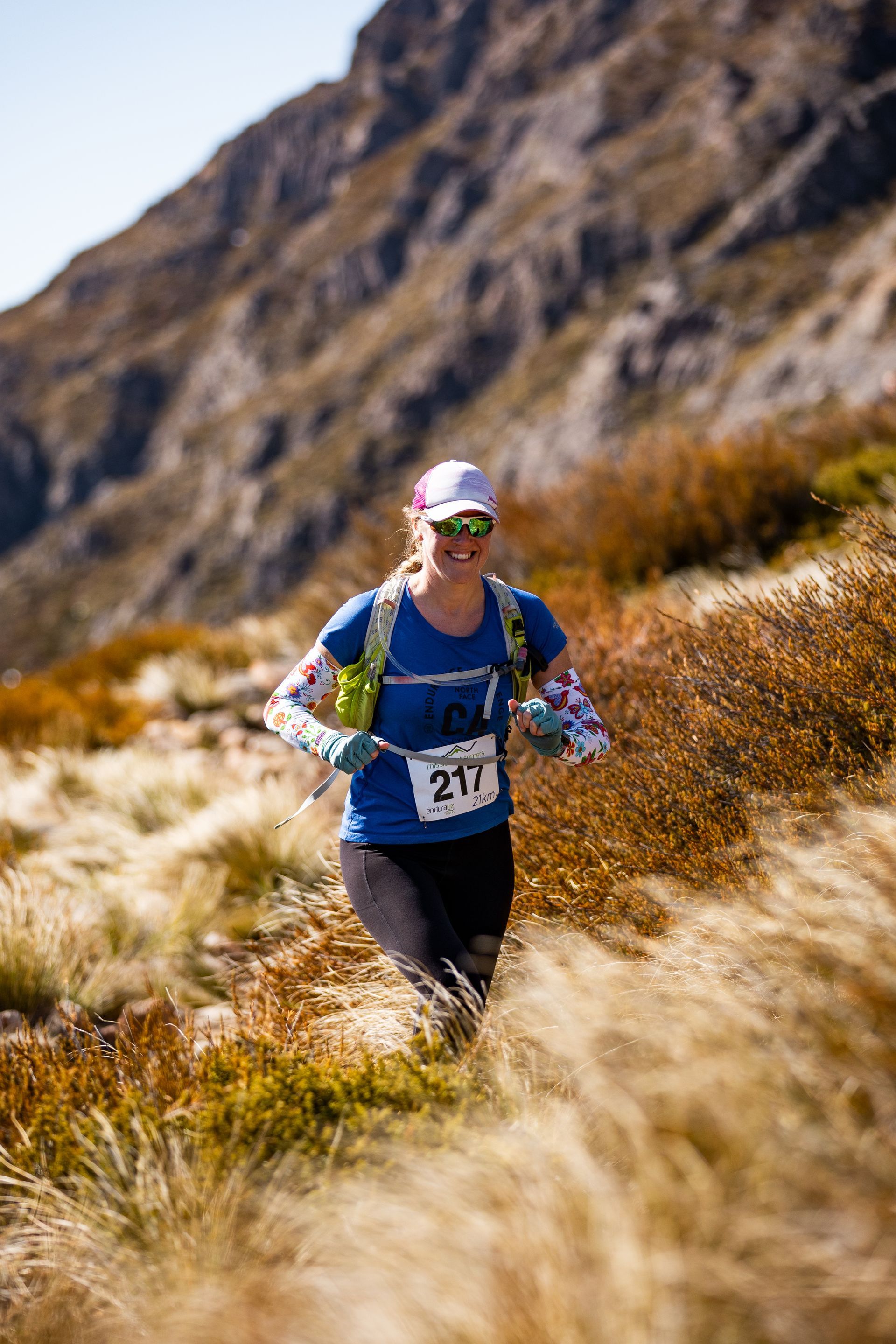 A woman is running on a trail in the mountains.