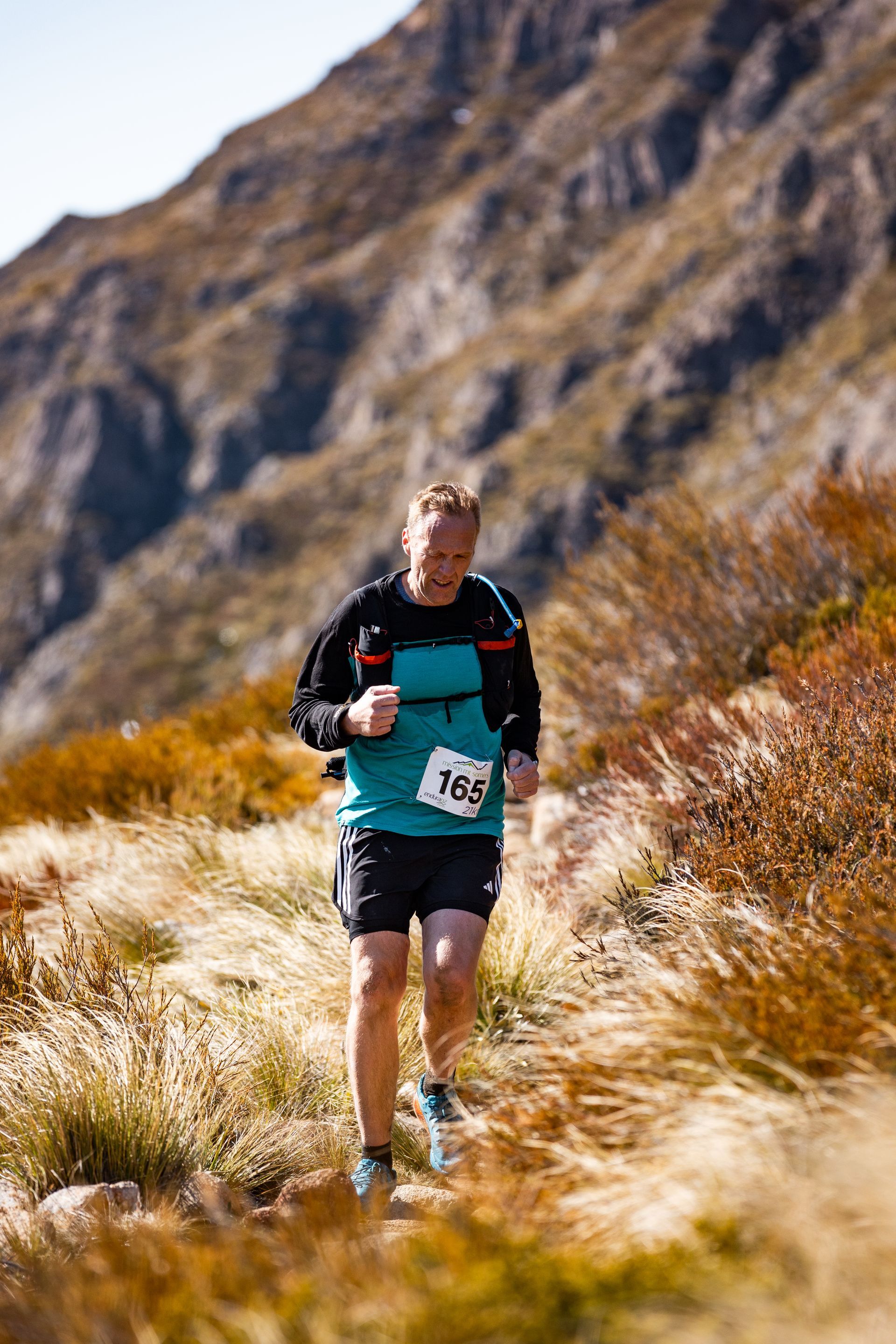 A man is running on a trail in the mountains.